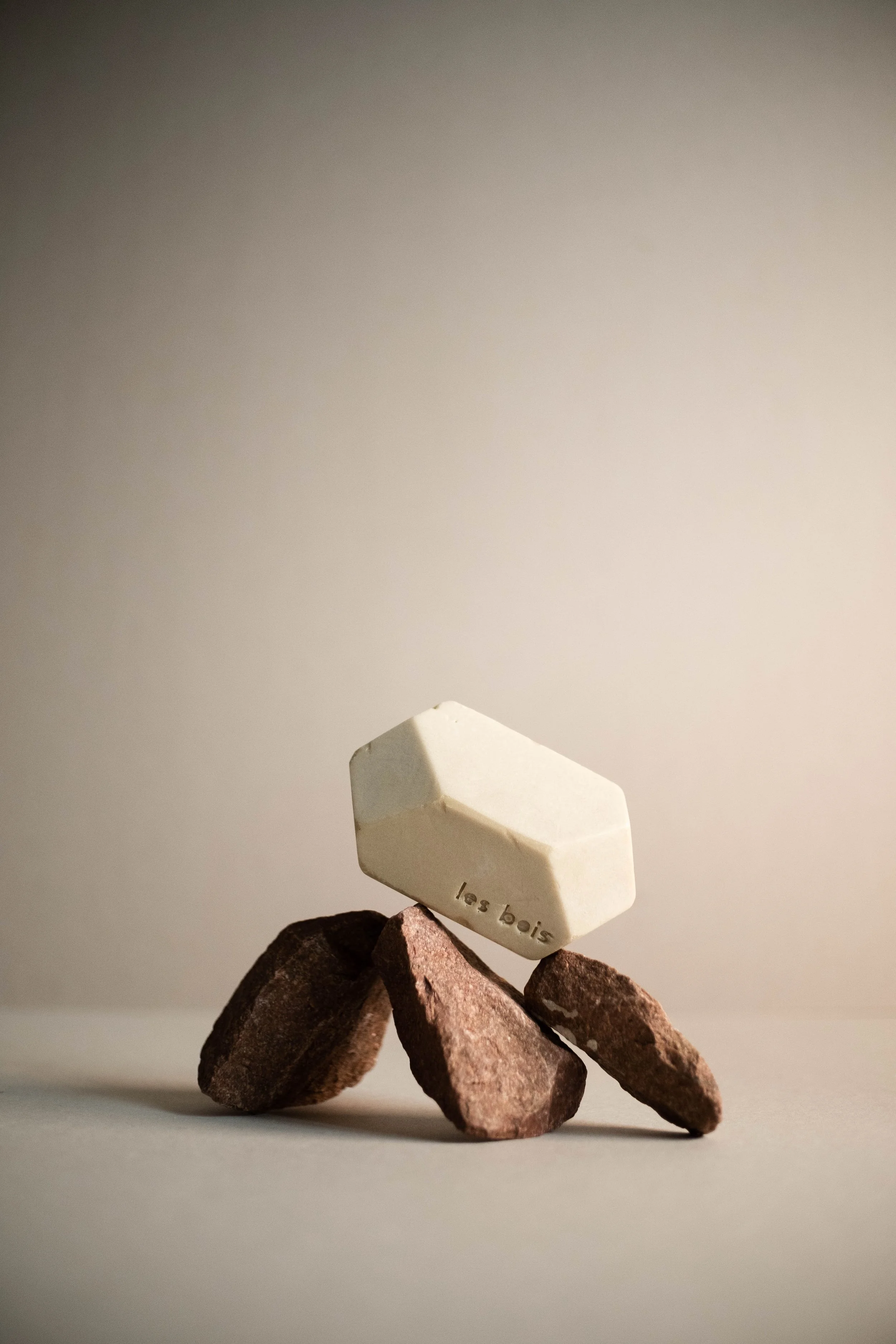 Une sculpture composée de quatre cailloux et d'une pierre blanche avec l'inscription 'les trois'.