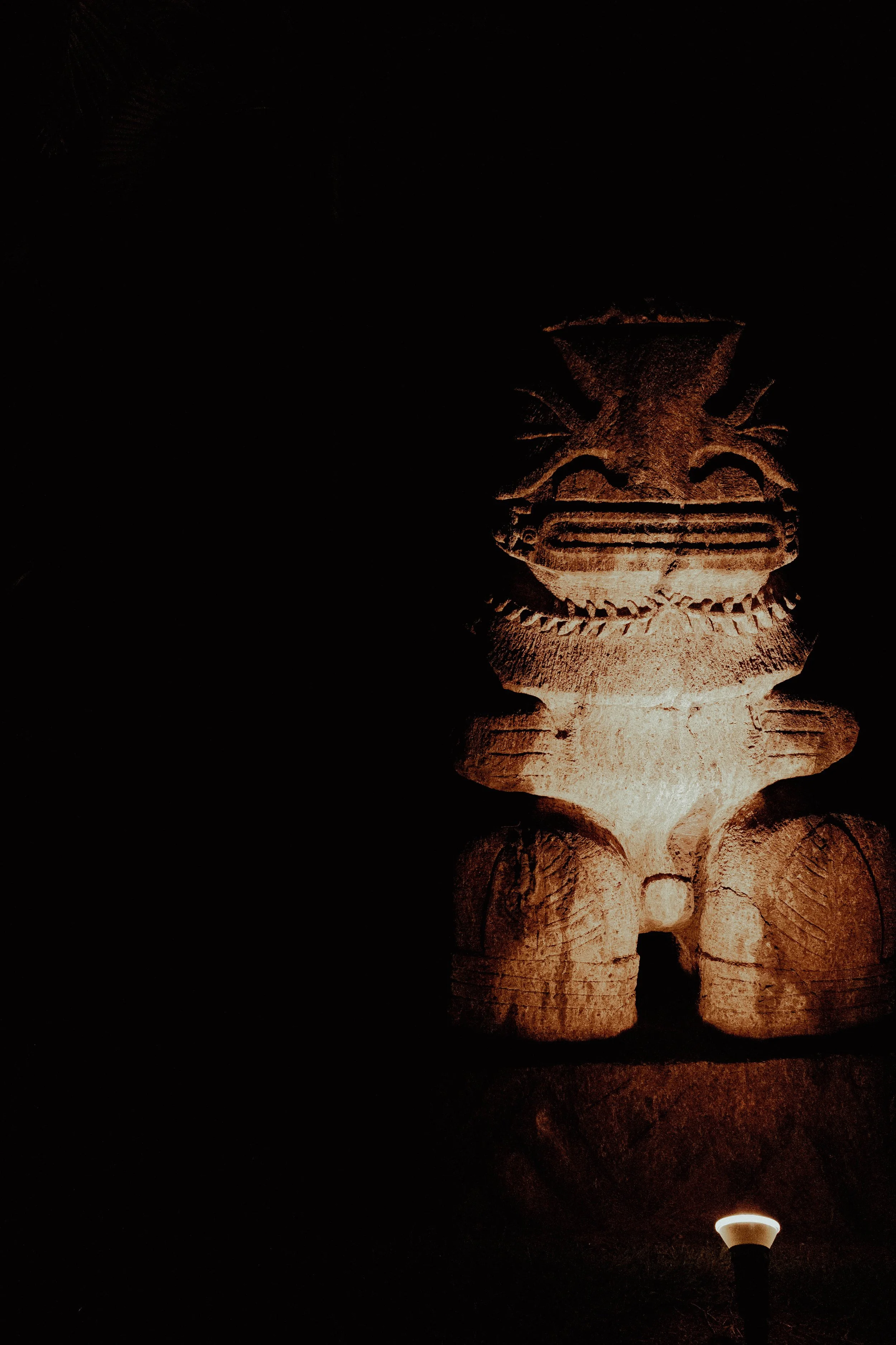 Statue ou sculpture en pierre représentant une figure mythologique ou religieuse, éclairée dans l'obscurité.