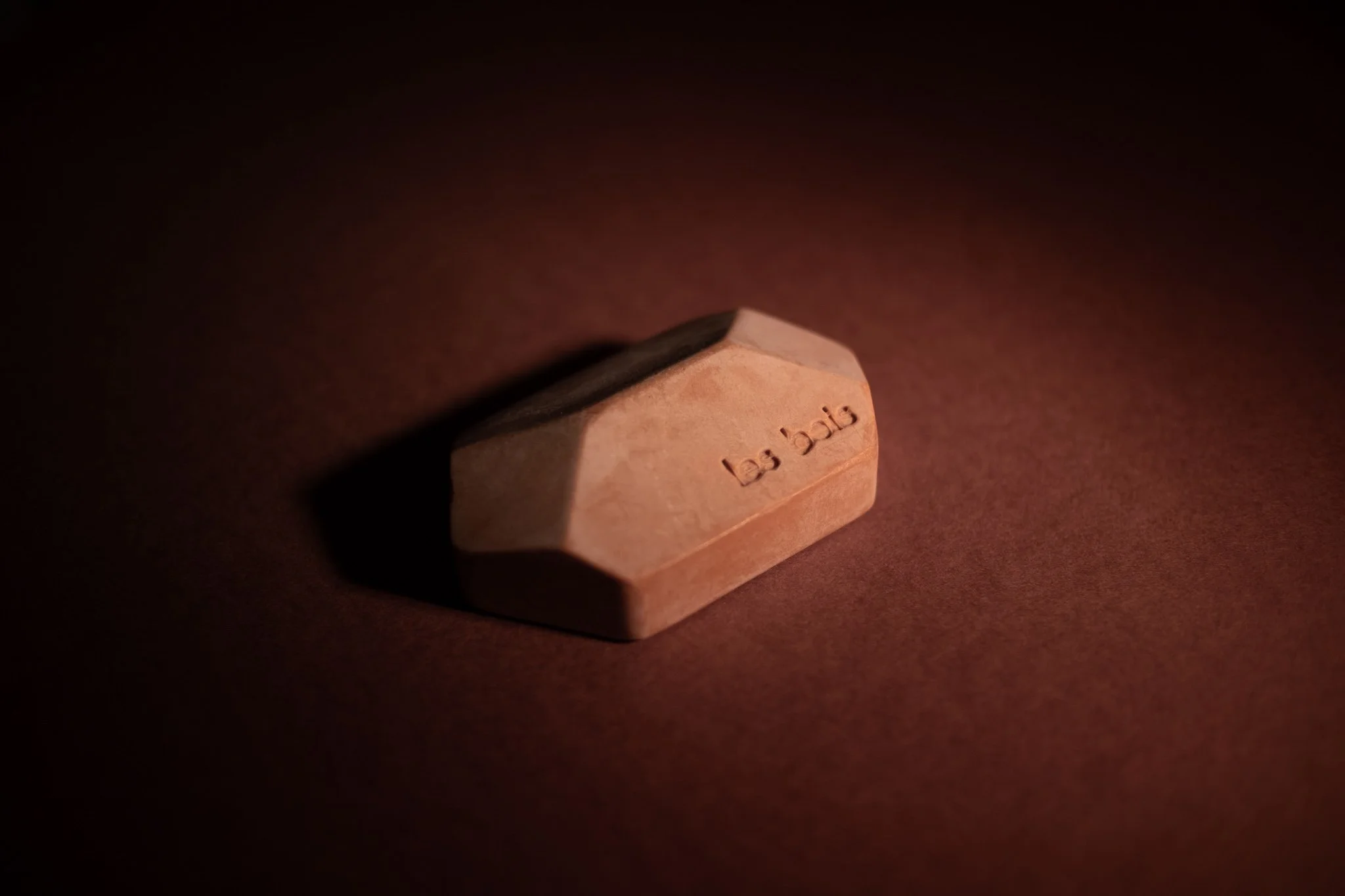 Une gomme rose sur une surface sombre, avec l'écriture 'la p'bi' enrichie.