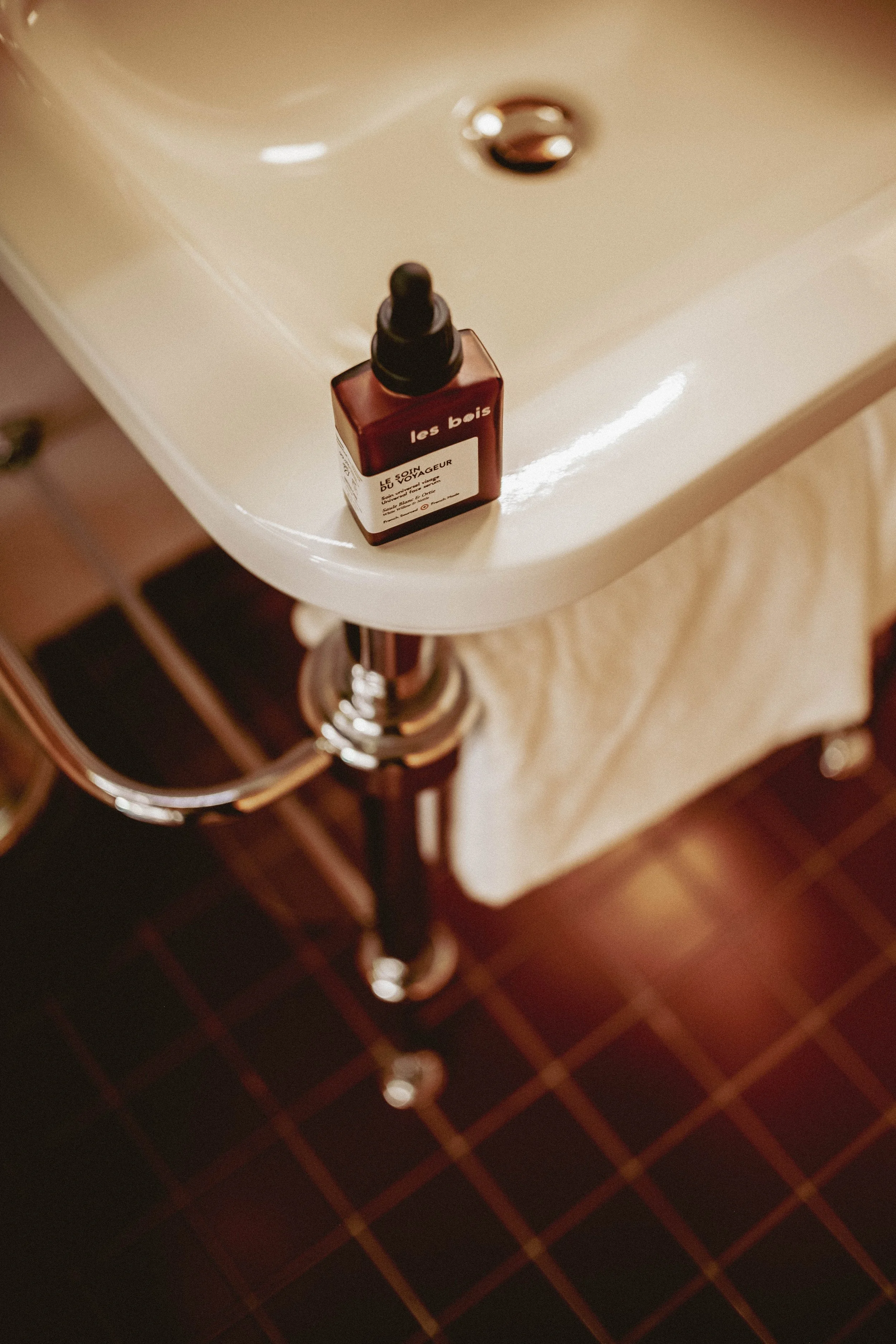 Une bouteille de savon au sol dans une salle de bain en verre teinté. 