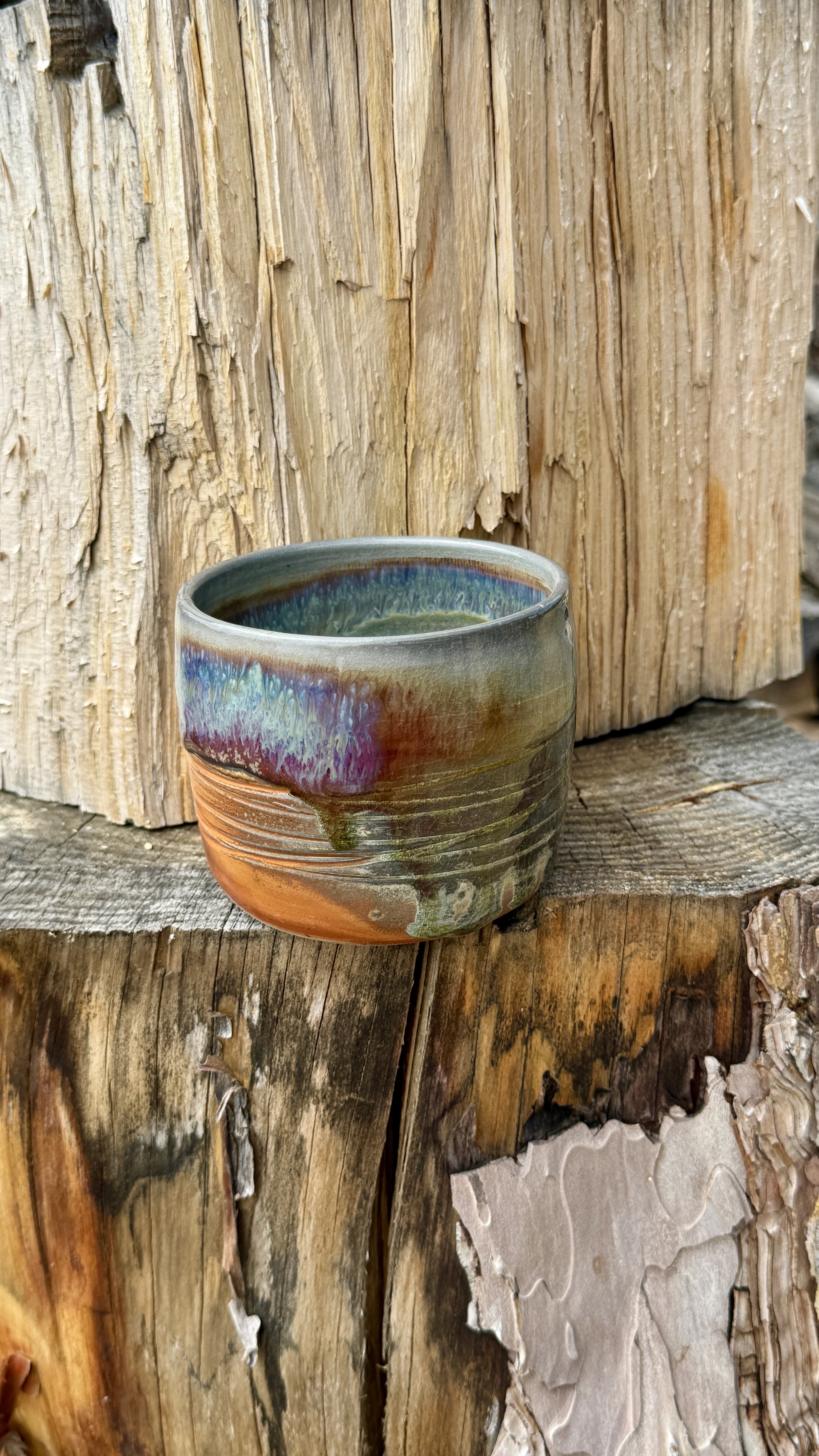 soda fired textured tea cup with orange, green, purple, grey and blue glazes