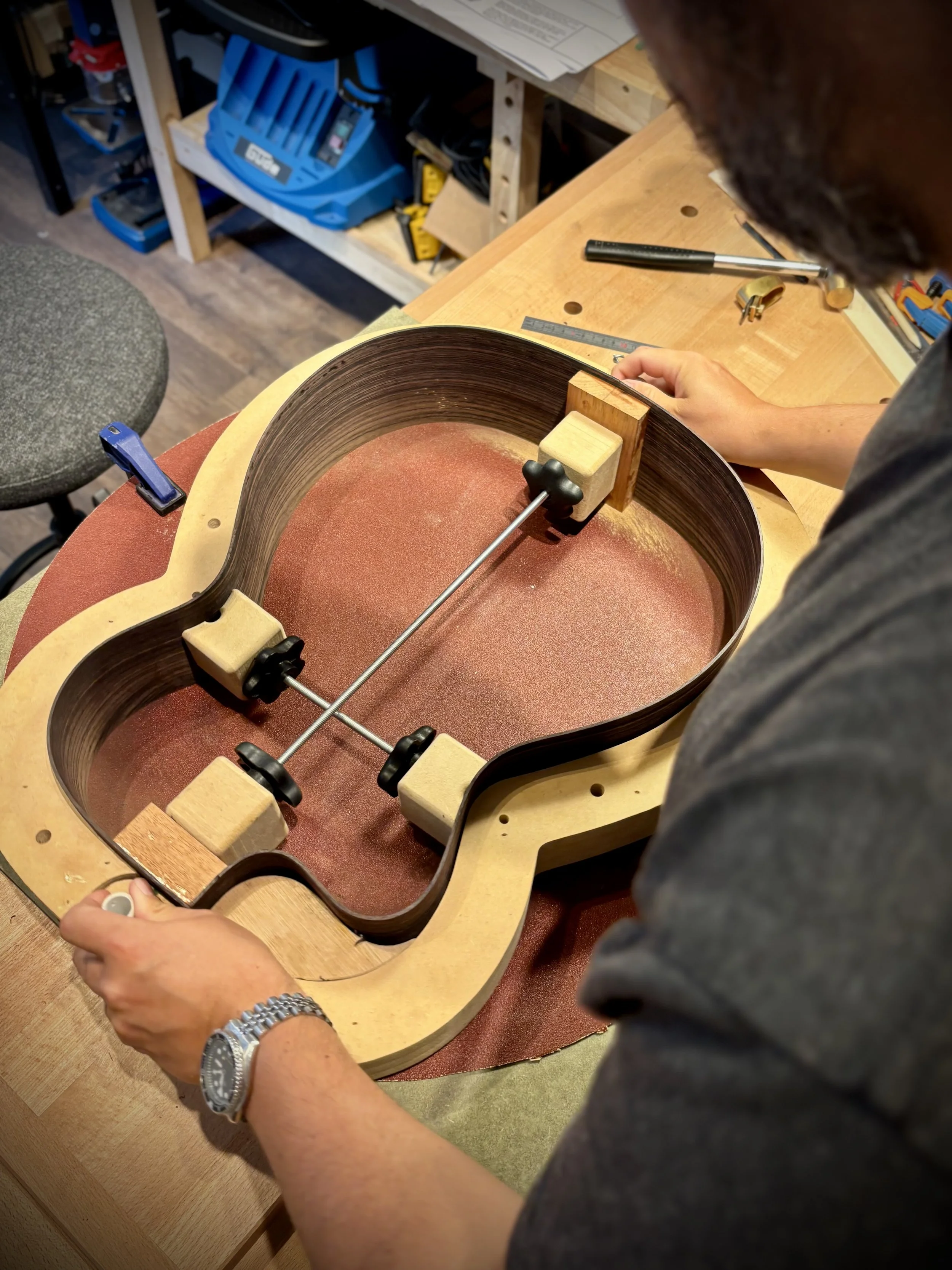 Il processo di incollaggio e invecchiamento di una chitarra acustica in un laboratorio di strumenti musicali.