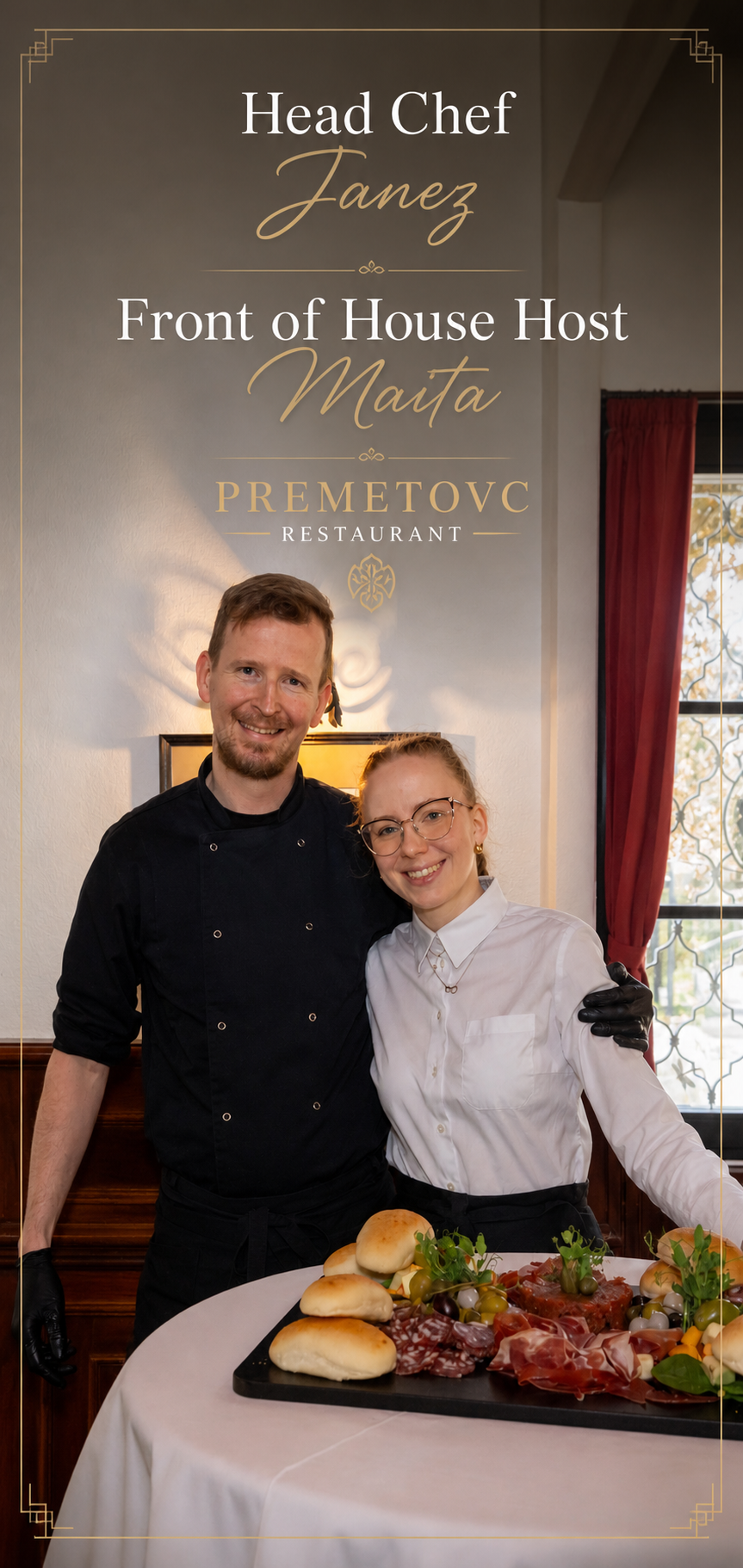 A chef and a server, a woman, standing together behind a table with a charcuterie board, bread, vegetables, and garnishes at a restaurant. Behind them is a wall with a sign that reads ‘Head Chef Janez, Front of House Host Maita, Premetovc Restaurant’.