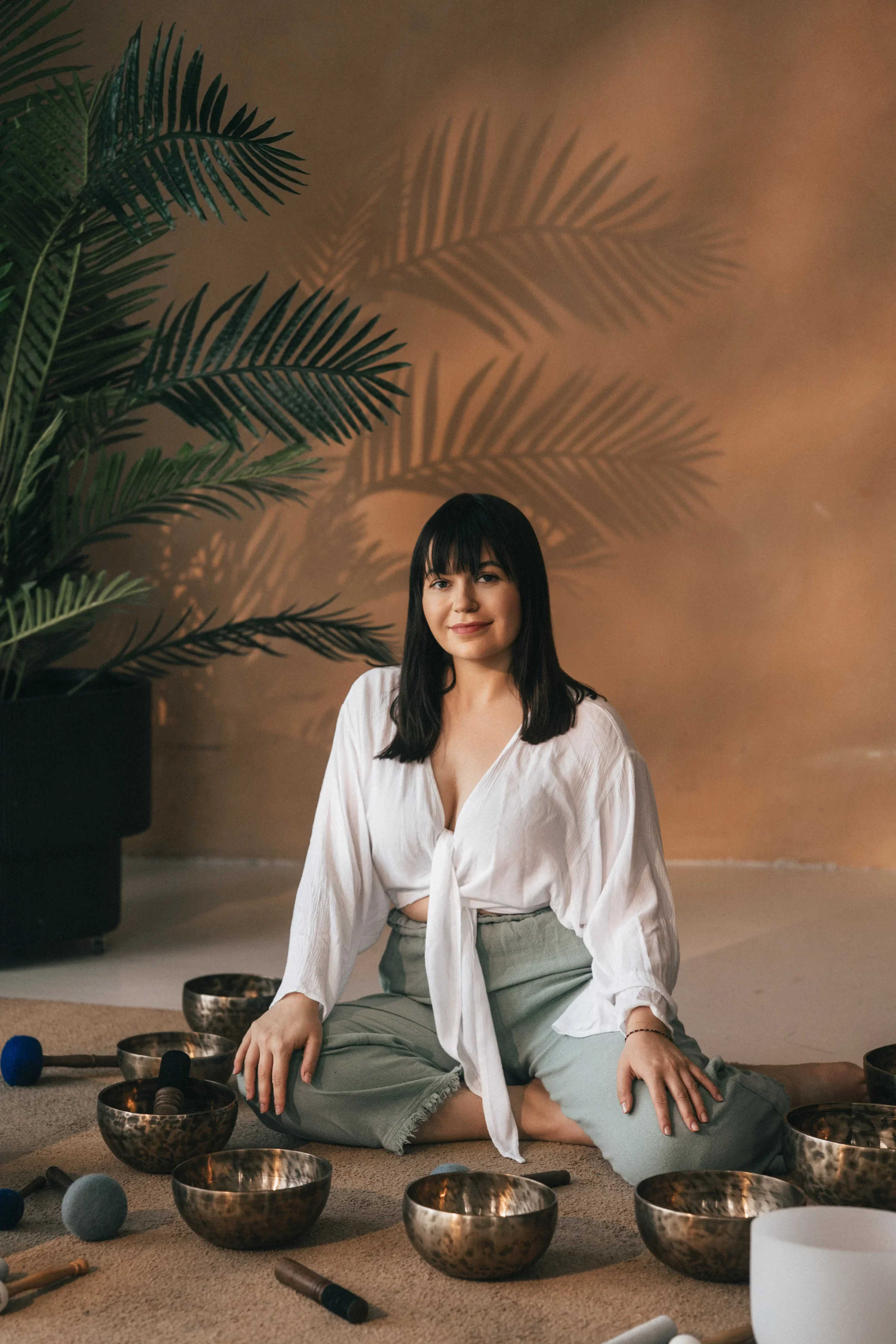 Vanessa Hartmann looking into the camera surrounded by Tibetan and crystal singing bowls during a trauma-informed sound healing session in Dubai.