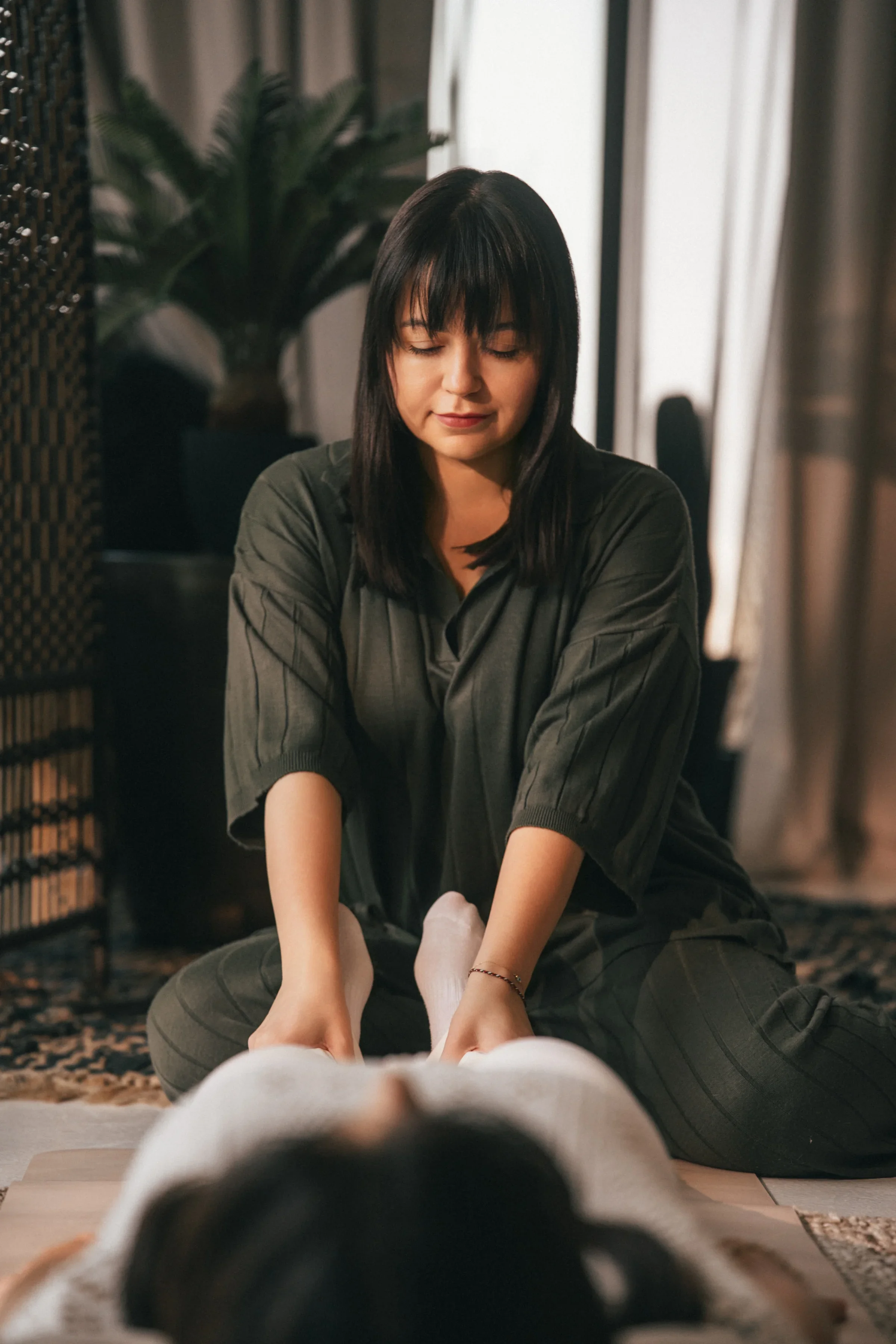 Breathwork facilitator Vanessa Hartmann providing grounding ankle support during a trauma-informed somatic breathwork session for nervous system regulation and emotional release in Dubai.