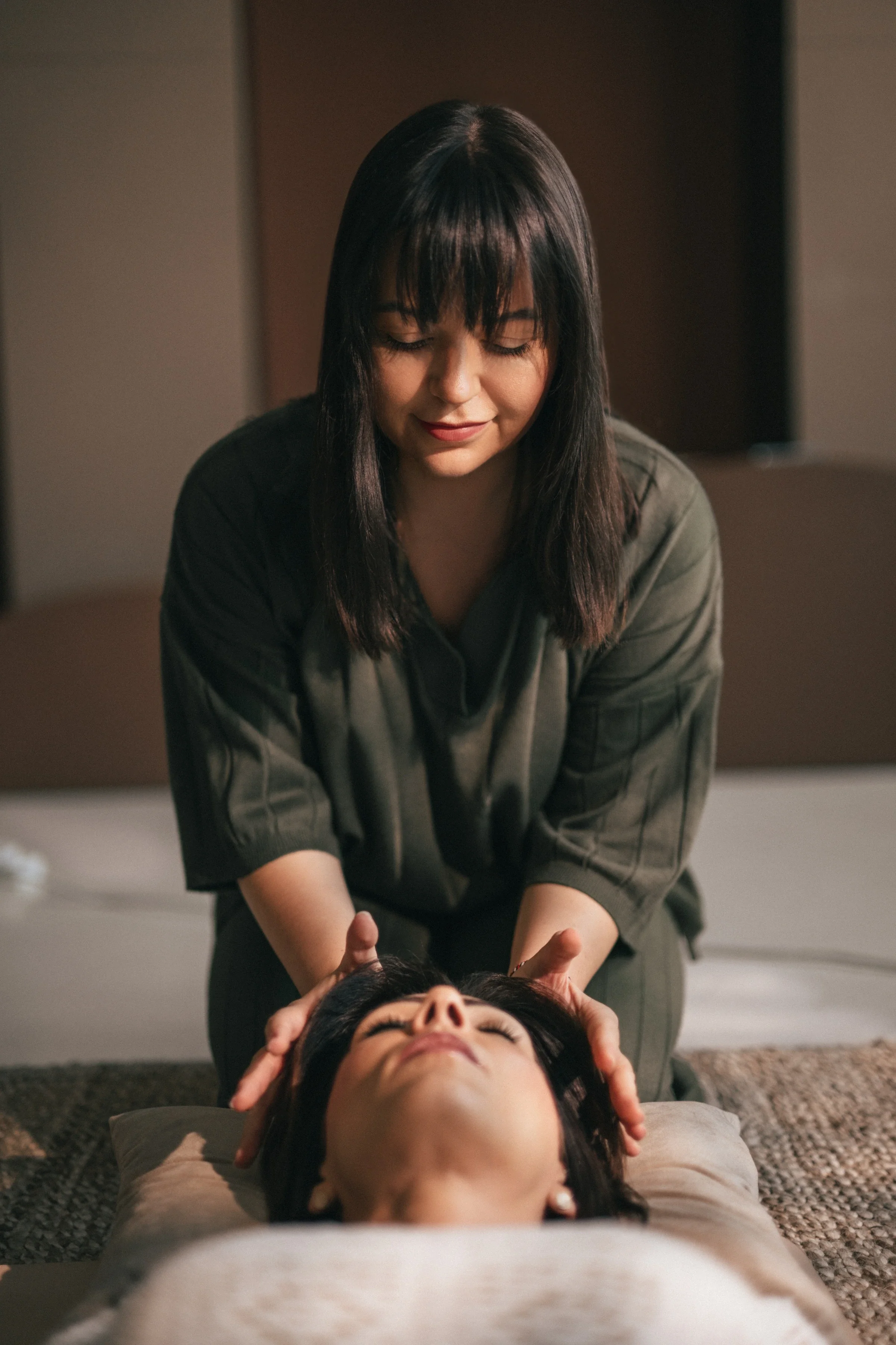Vanessa Hartmann offering gentle non-contact head support during a trauma-informed somatic breathwork session to promote relaxation and nervous system regulation in Dubai.