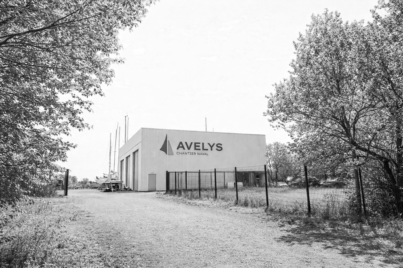 Une installation navale avec un bâtiment portant le nom 'AVELY'S CHANTIER NAVAL', entourée de verrous, avec des arbres environnants et quelques bateaux en arrière-plan.