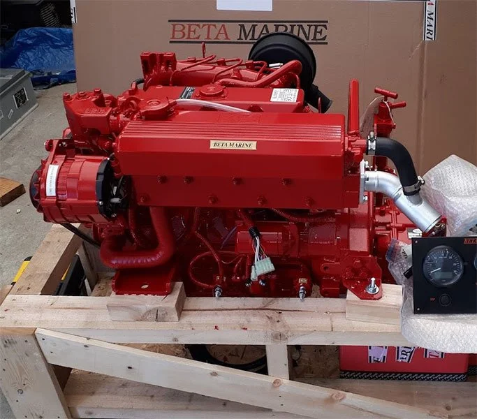 Moteur marine rouge placé sur une plateforme en bois, avec un panneau de contrôle à côté.