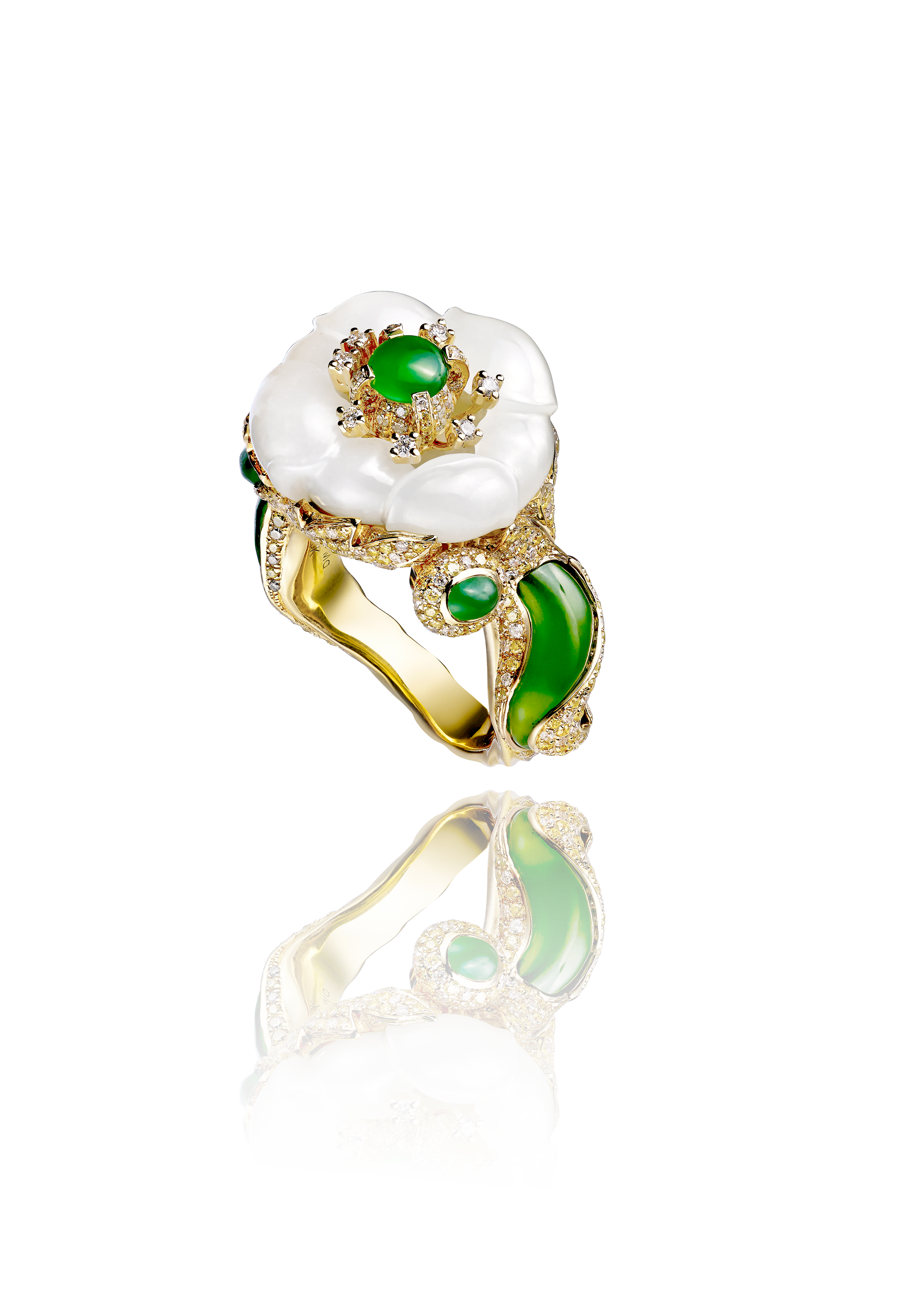 A luxurious ring featuring a large white flower made of pearl with a green gemstone center, surrounded by encrusted diamonds and green gemstones on a gold band.