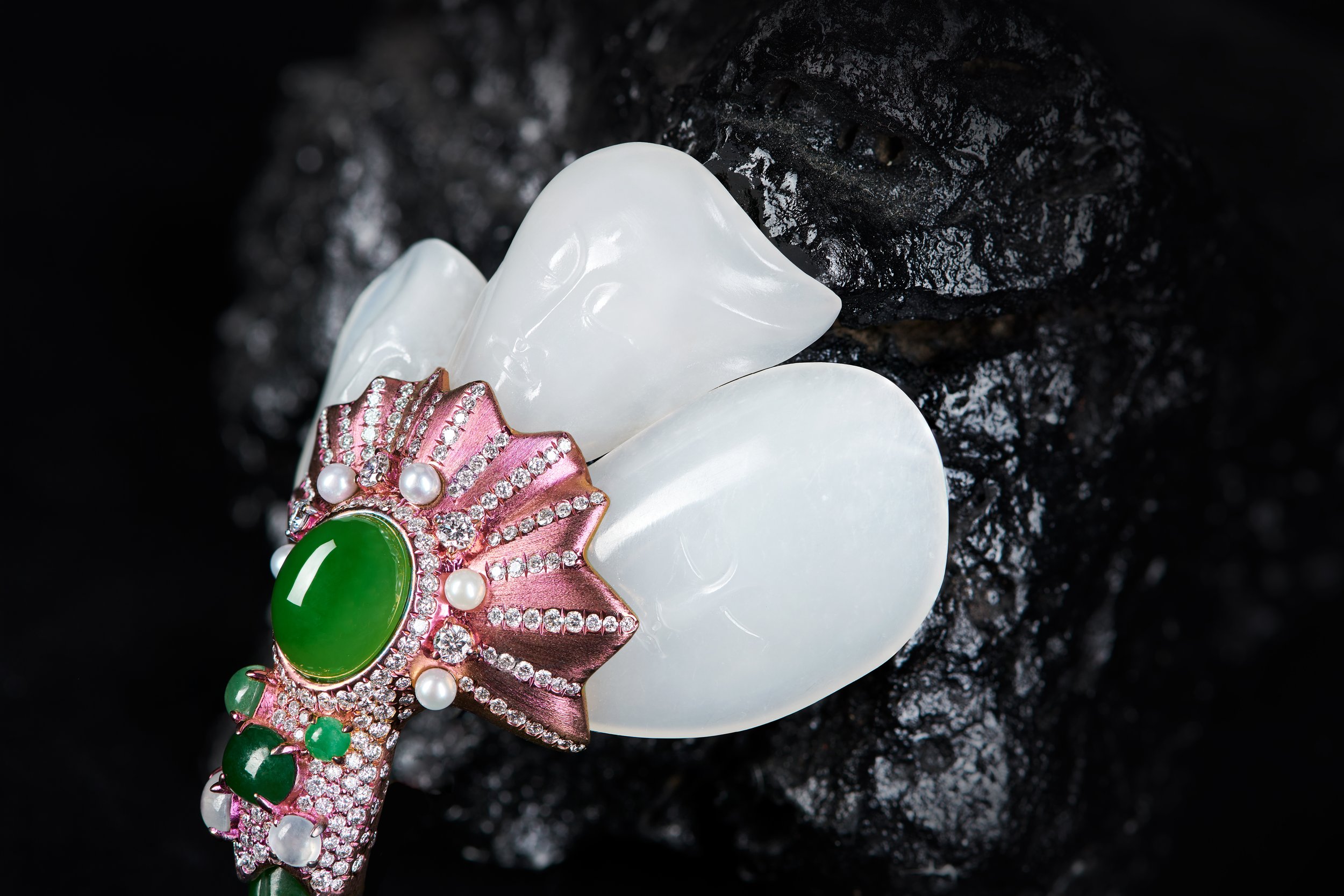 A brooch shaped like a banana leaf, crafted from white Hetian jade. The piece is set with a piece of Hetian jadeite and diamonds, while the main stem is constructed from pink titanium.