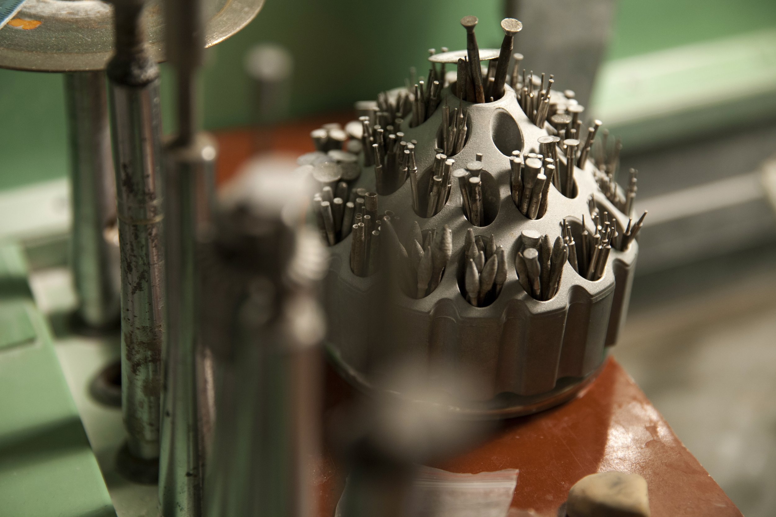 A collection of drill bits and metal tools stored in a round holder on a workbench.