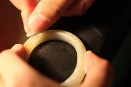 A person is polishing a Hetian white jade bracelet.