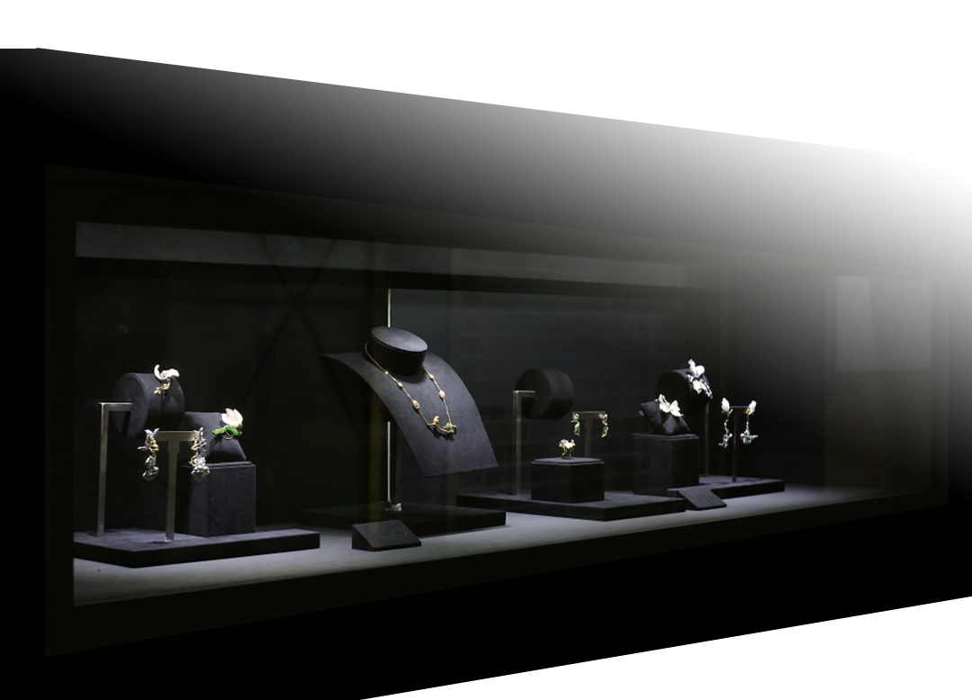 Jewelry display case featuring necklaces, earrings, and rings on black stands and velvet cushions in a dark room.