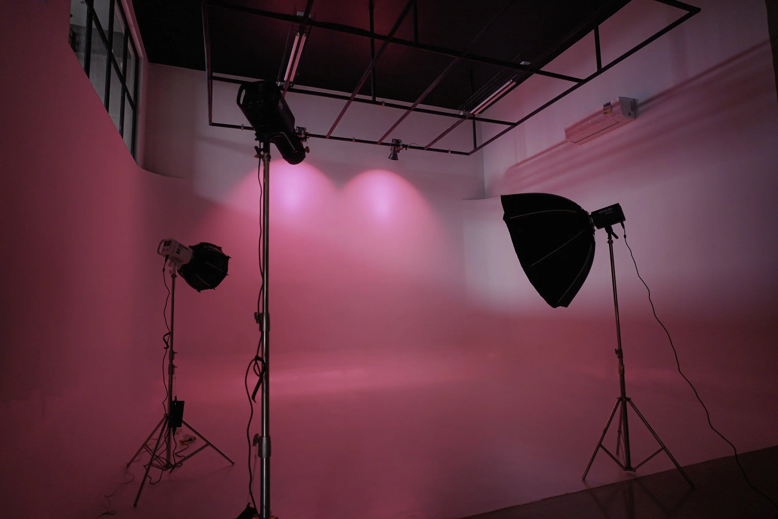 Photography studio setup with pink lighting, two softboxes on stands, and a backdrop
