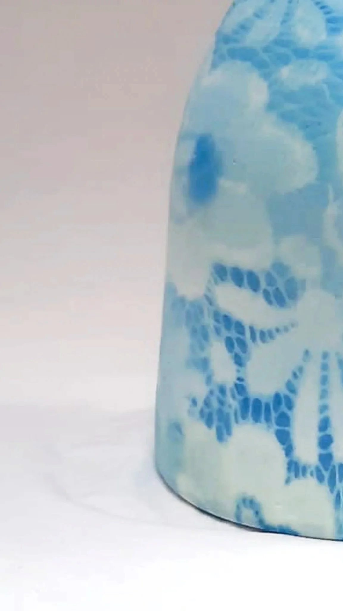 Un verre bleu avec un motif de squelette de crâne et de bras en style mosaïque ou découpé, posé sur une surface blanche.