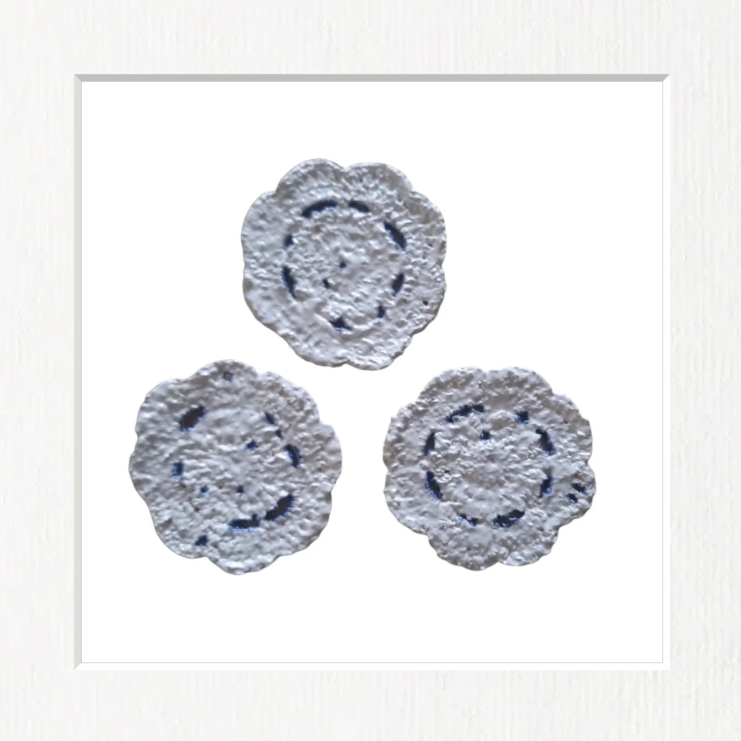 Trois biscuits ronds avec un visage souriant en relief, disposés en triangle sur fond blanc.