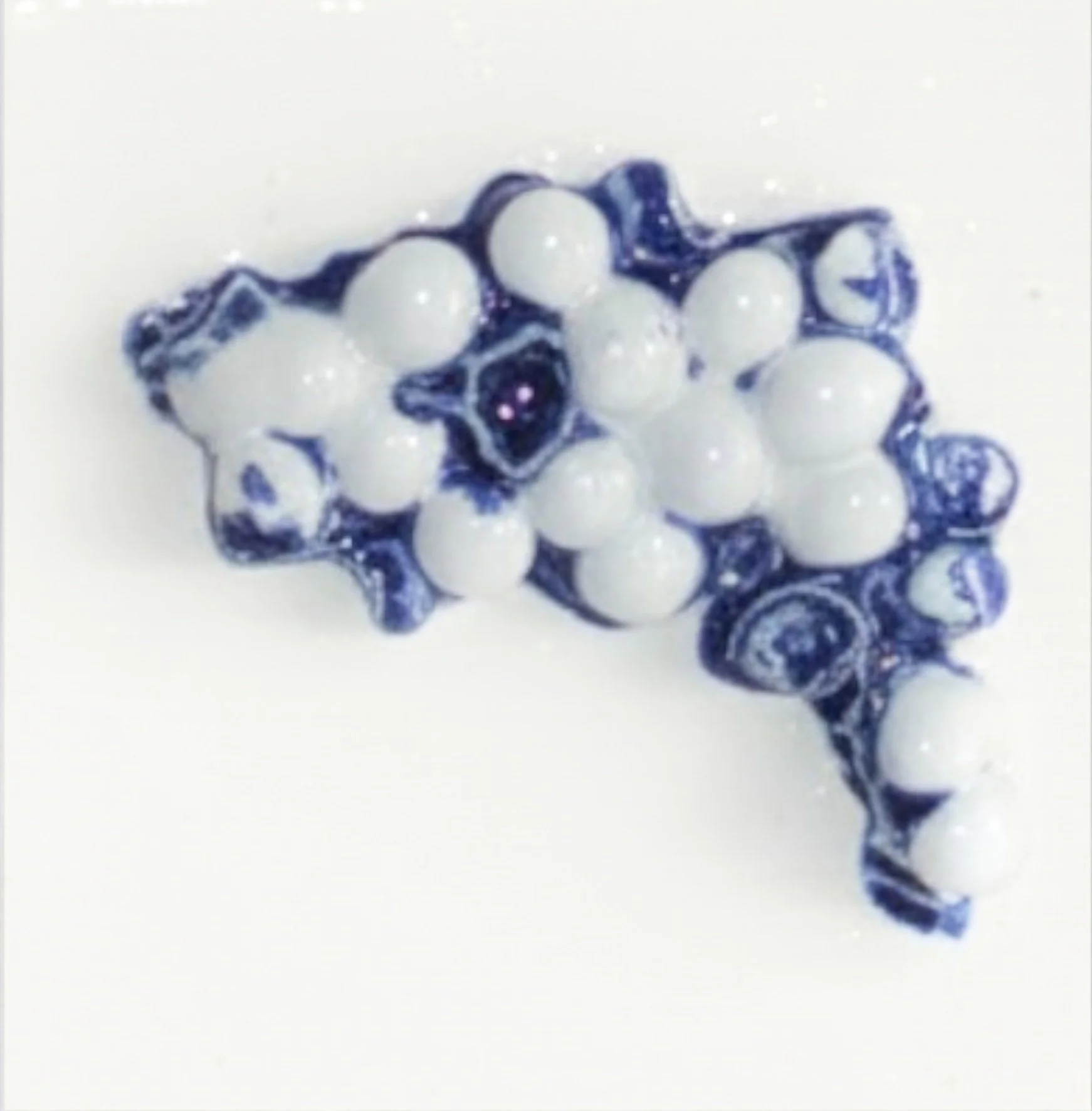 Une broche en forme de nuage avec des perles blanches et un dessin en bleu.