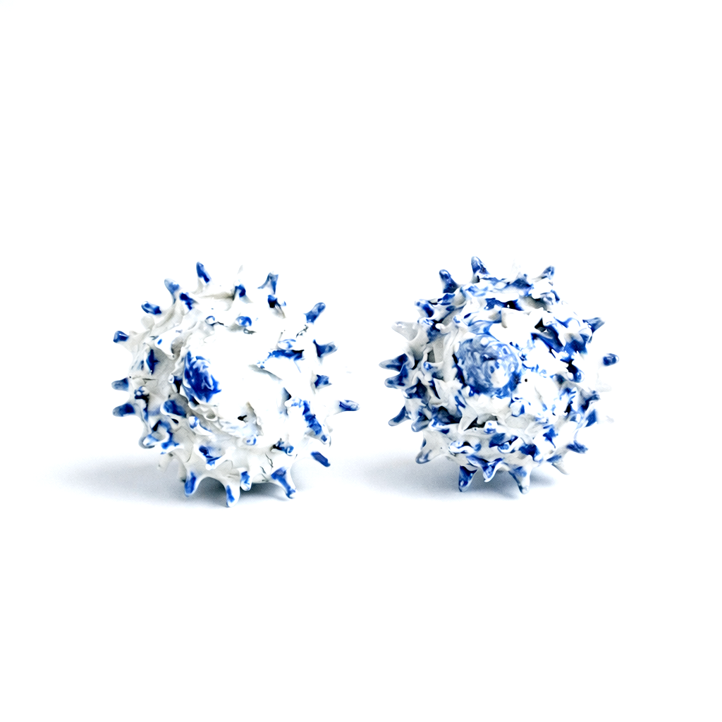 Deux balles de rugby blanches et bleues avec des piquants, posées sur un fond blanc.