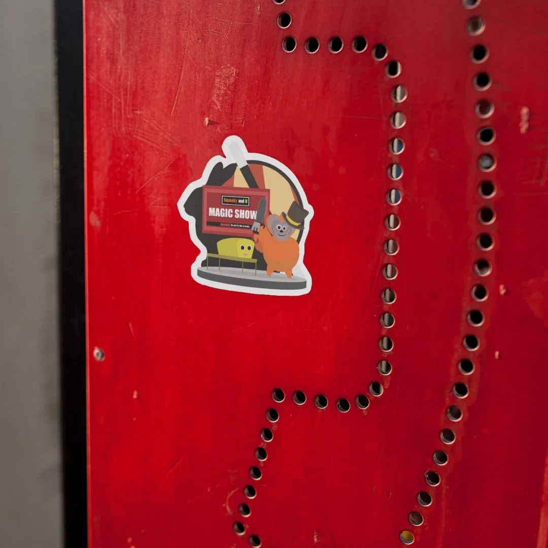 A sticker of a koala with a top hat and a magician's wand, standing next to a yellow character, in front of a red background with small holes.