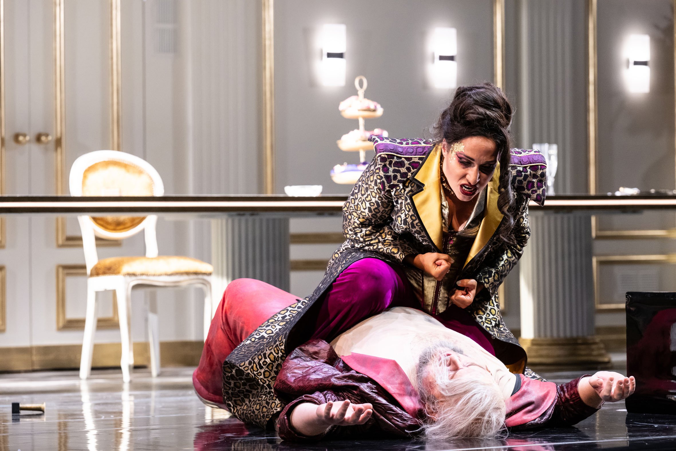 Szene aus einem Theater, eine Frau in farbiger Kleidung liegt auf dem Boden, eine andere Frau schreit oder ruft laut, beide in einer dramatischen Pose.