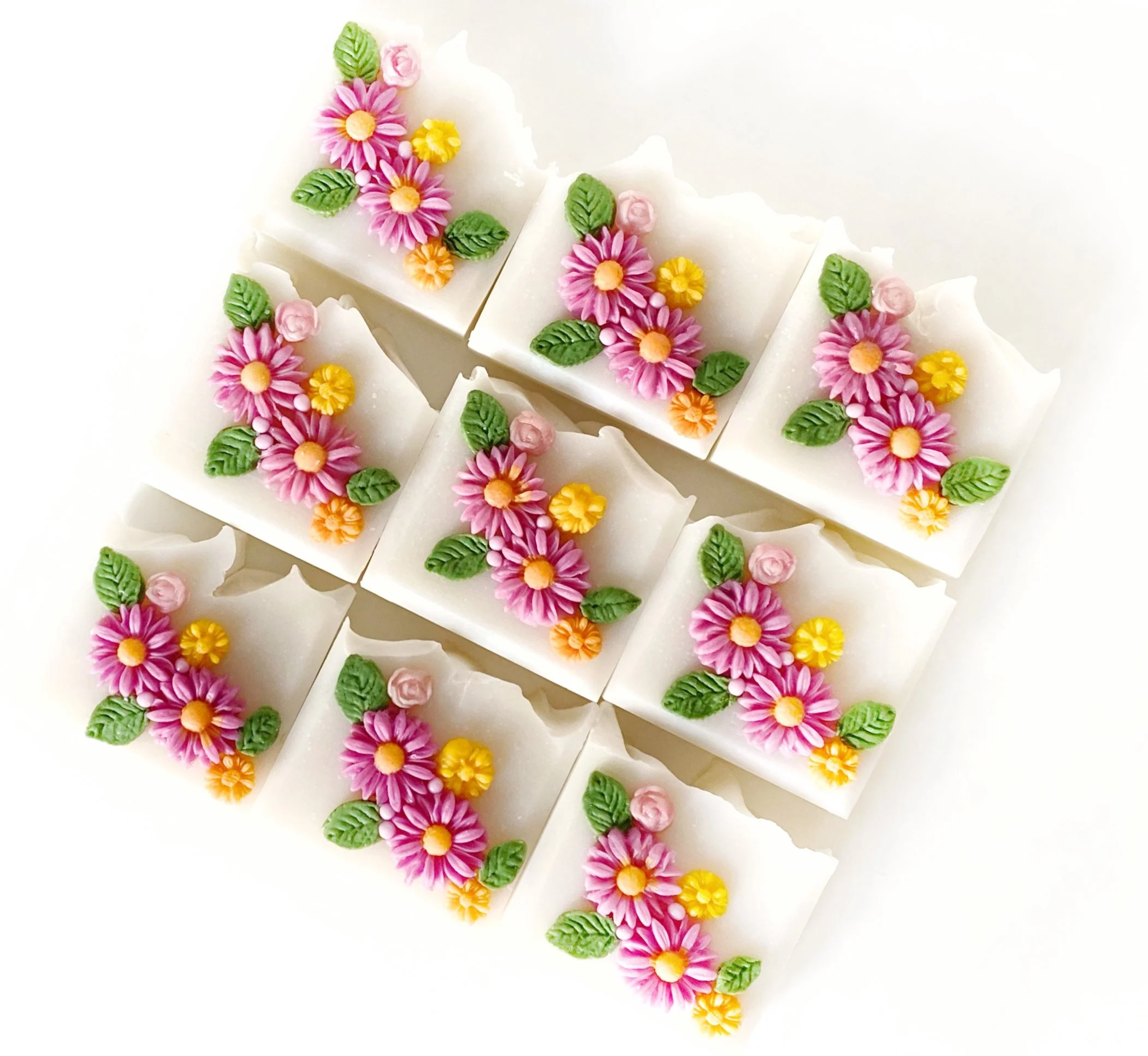 Decorative soap bars with pink, yellow, and orange flower and leaf designs on a white background.