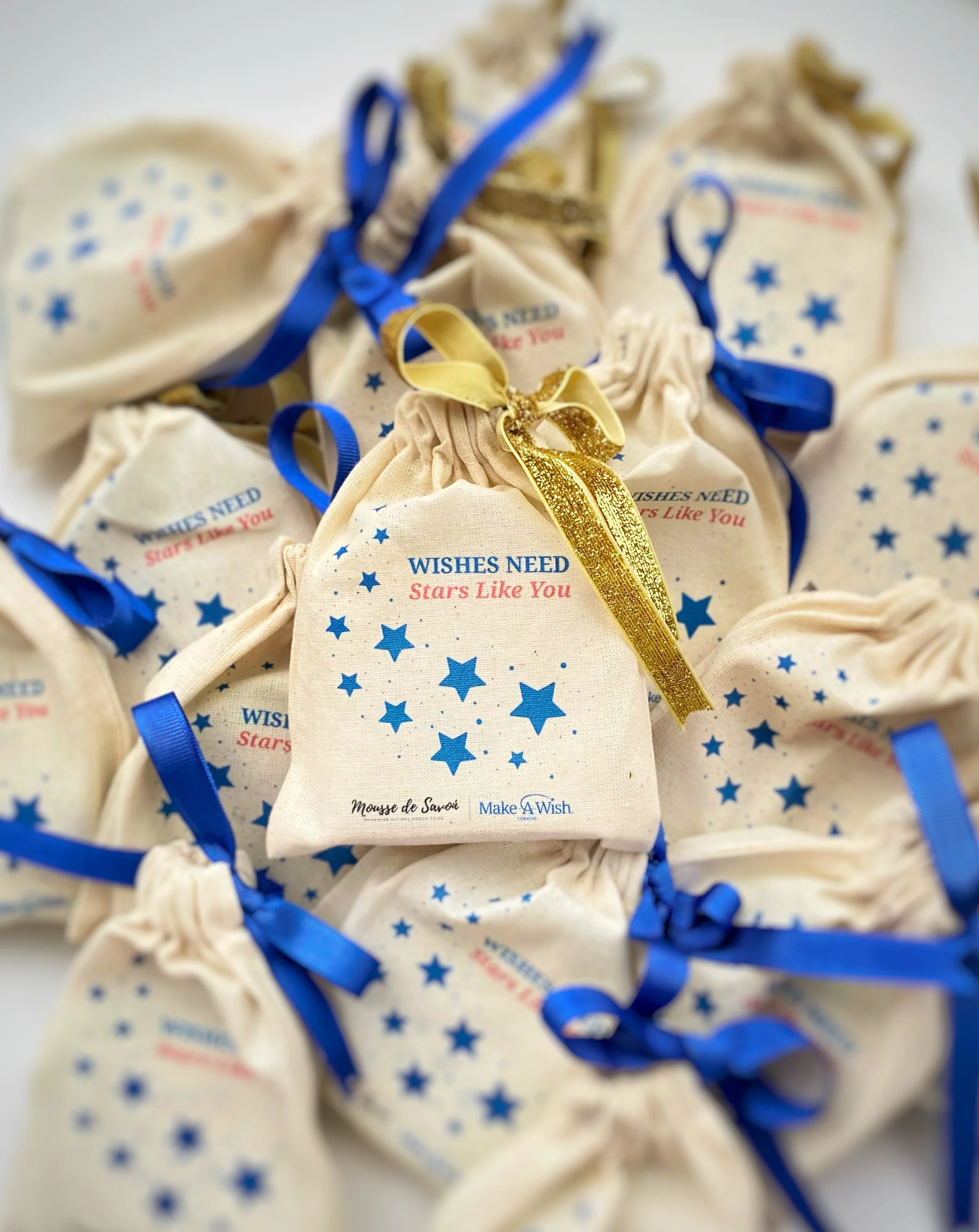 Small fabric pouches with blue stars and red text, tied with blue and gold ribbons, labeled 'Wishes Need Stars Like You'.