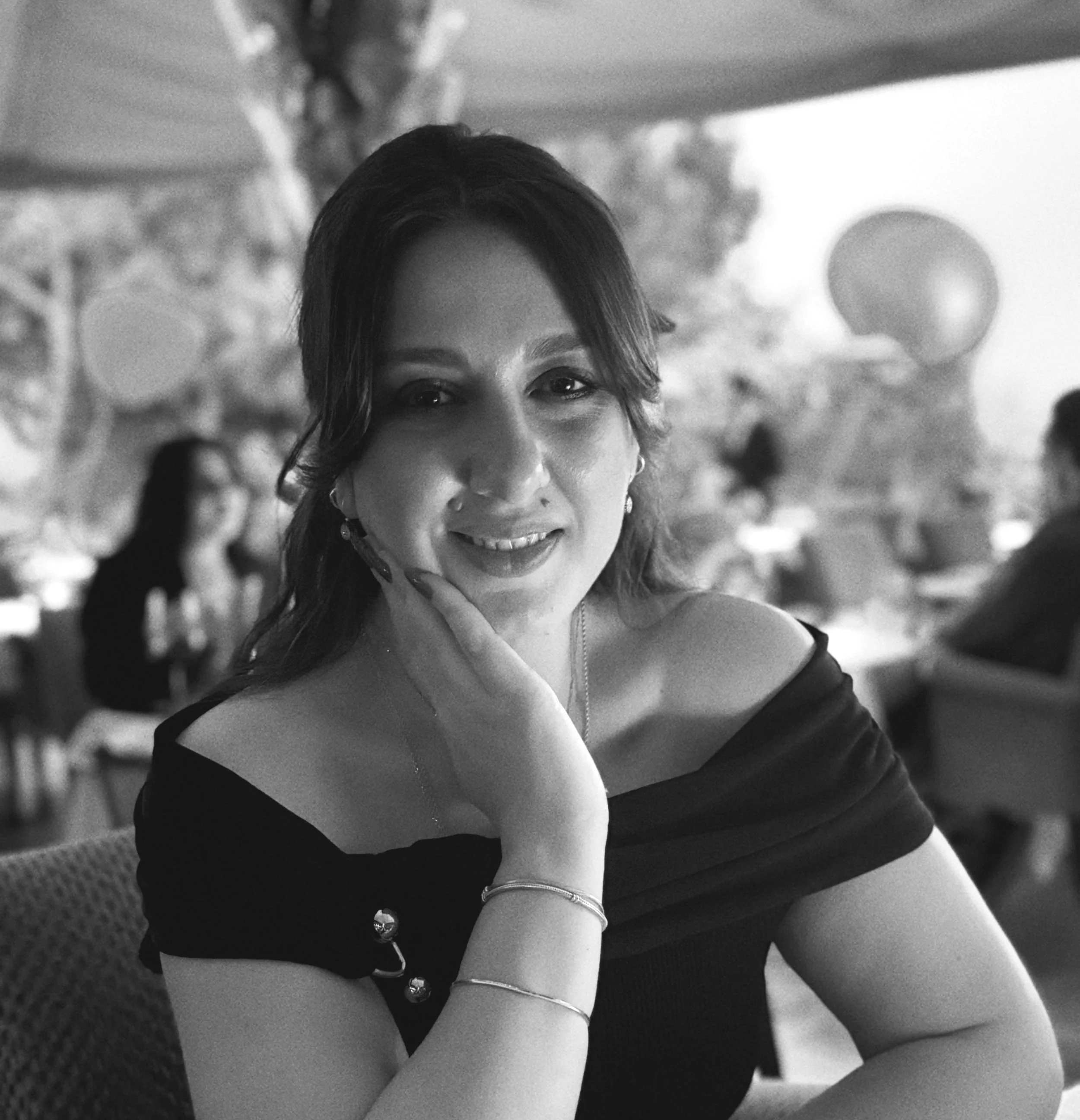 Kadın bir restoranda otururken poz veriyor, yakın planda ve siyah beyaz fotoğraf.