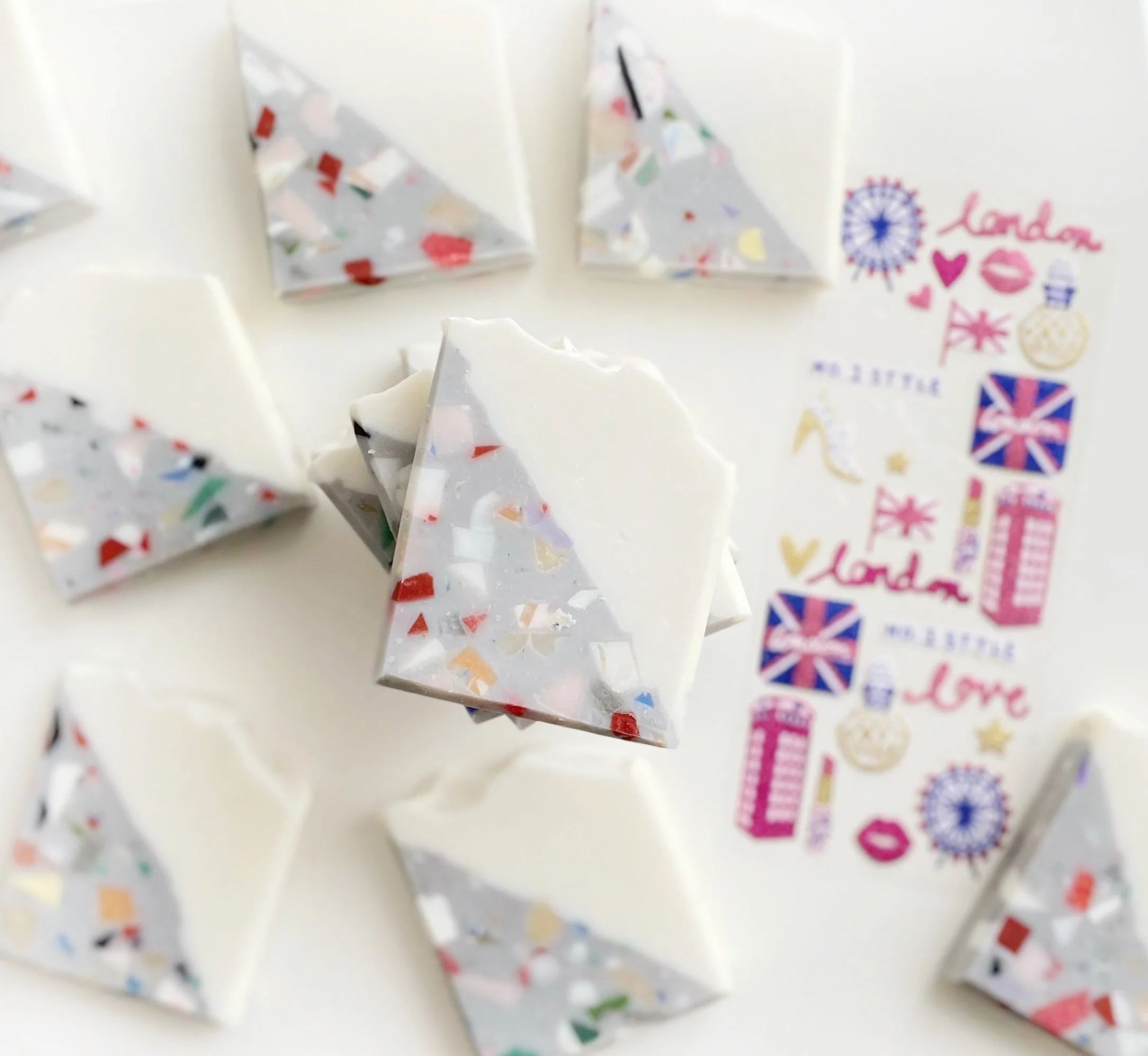 Assorted holiday-shaped soap bars with confetti in silver packaging, decorated with London and UK-themed stickers.