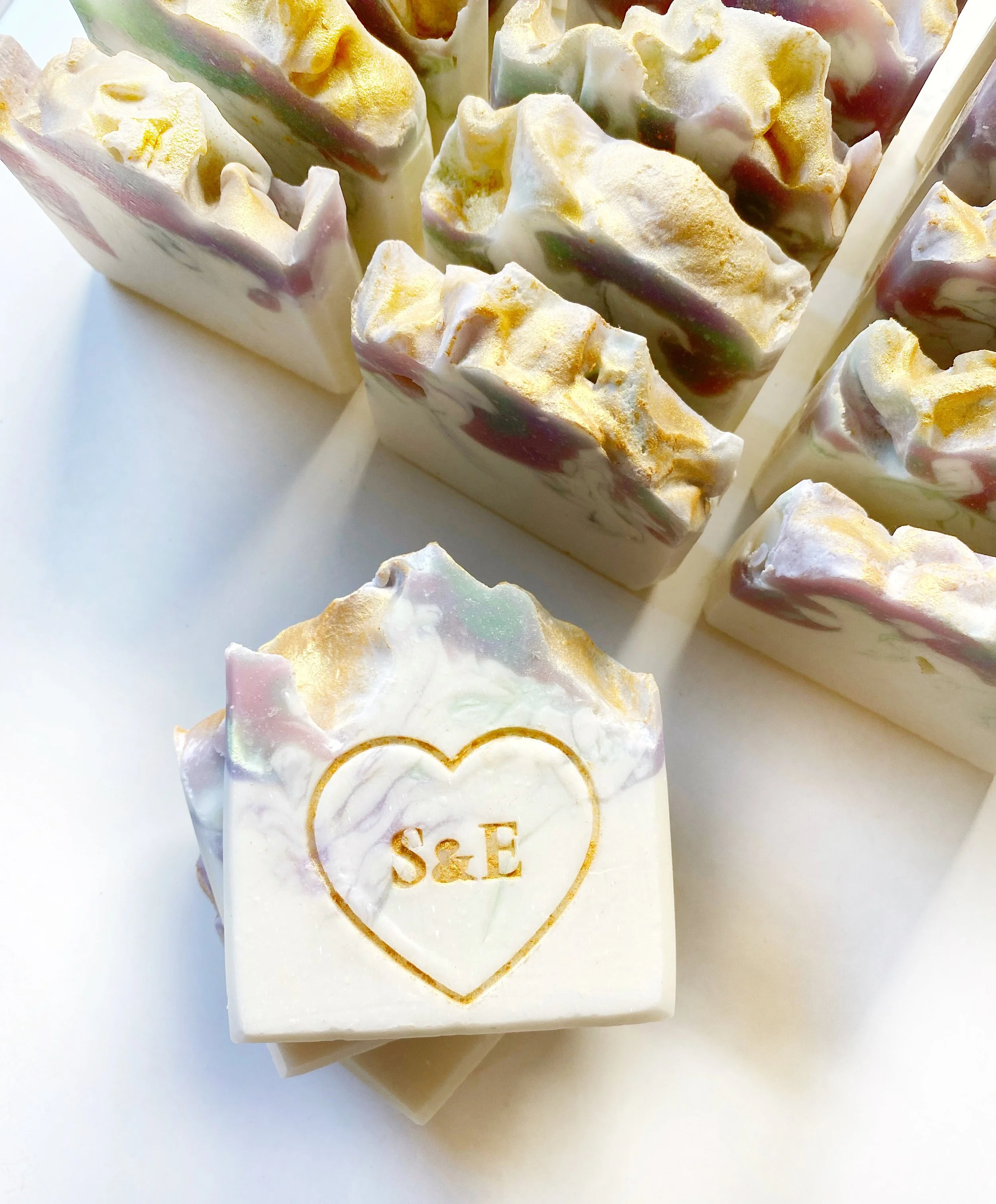 Marbled soap bars with gold accents and the initials S & E engraved inside a heart