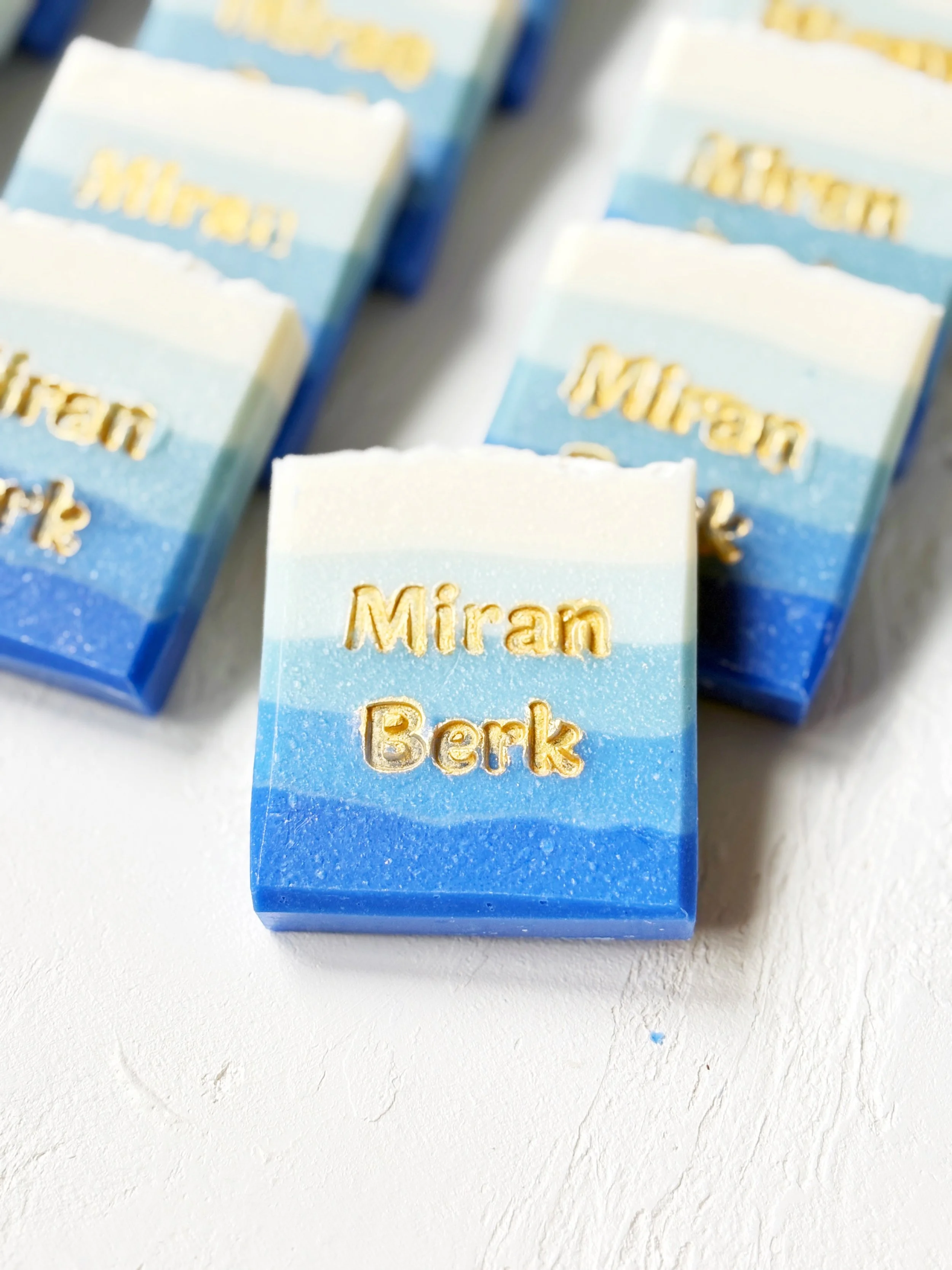 Blue and white layered soap with the words 'Miran Berk' embossed in gold on top.