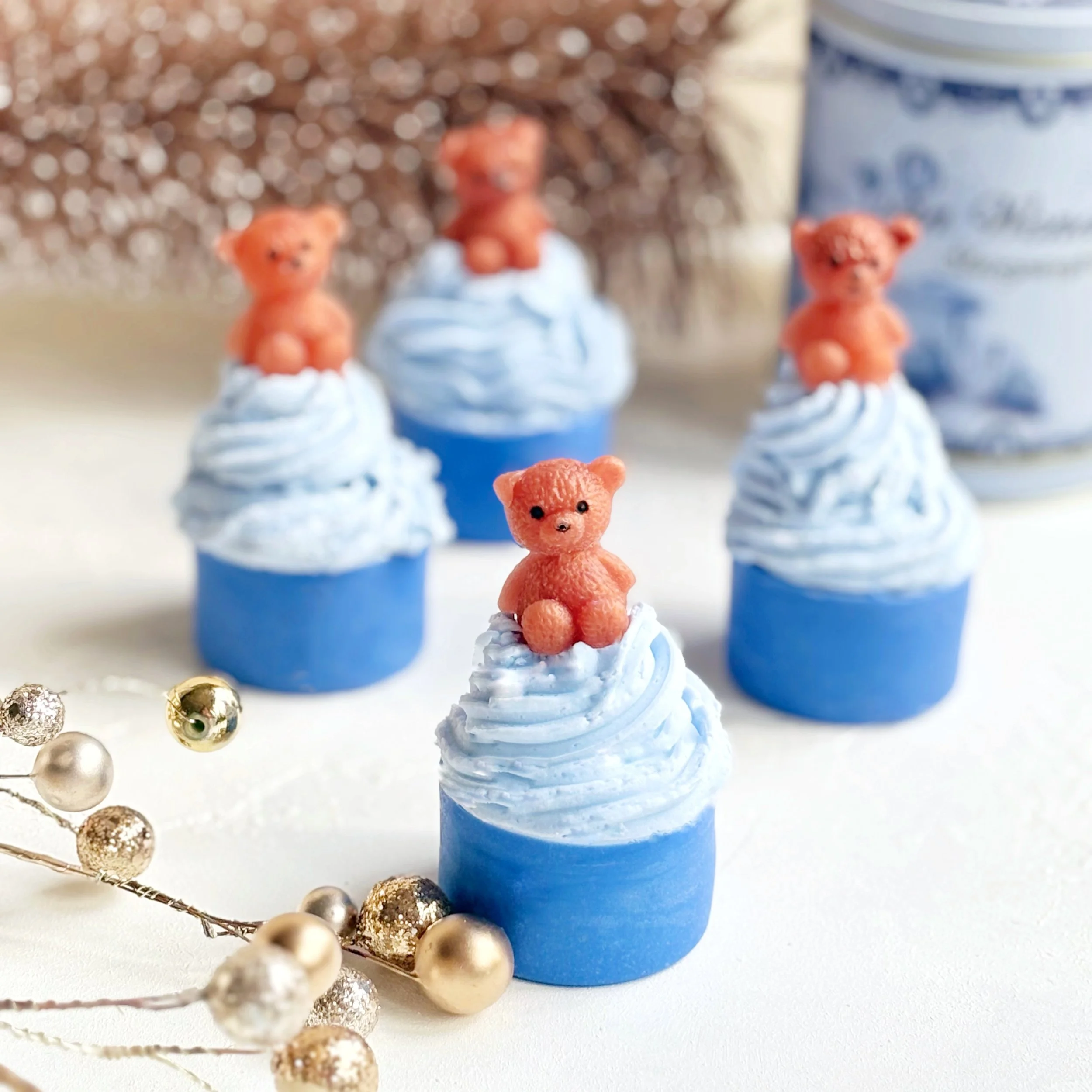 Miniature cupcake soaps with blue frosting and teddy bear toppers, decorated for a festive occasion.