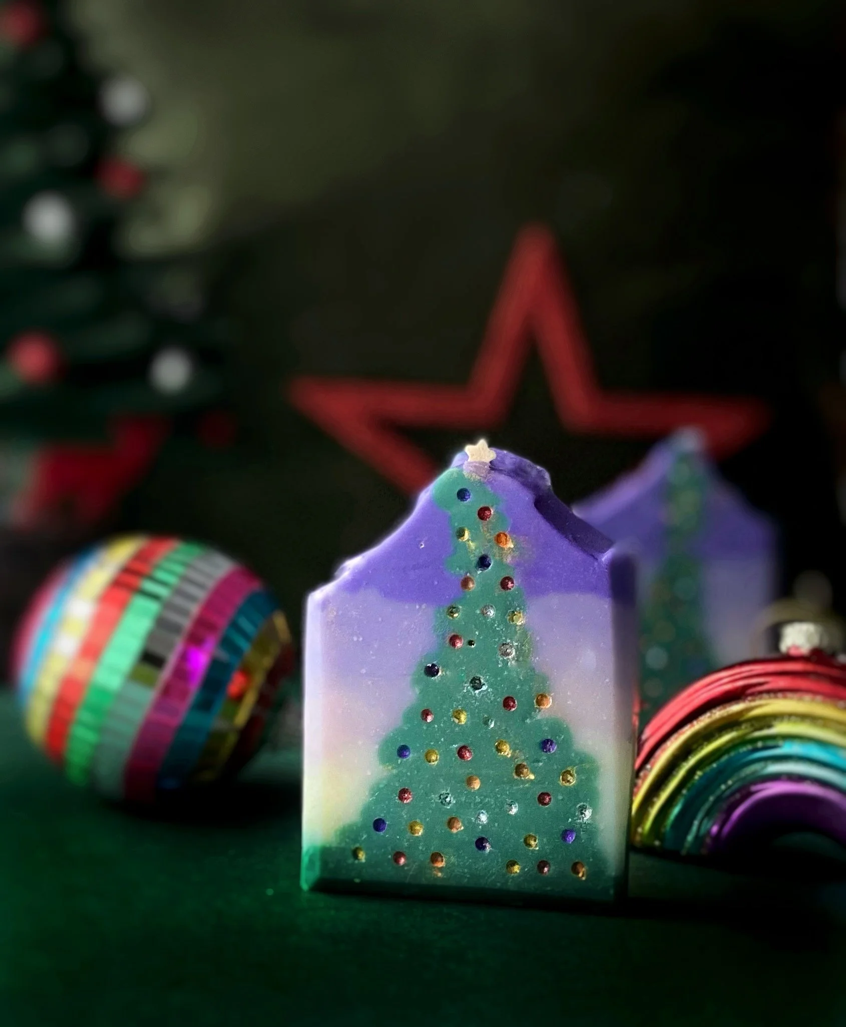 Christmas candles decorated with colorful, glittery Christmas trees, with ornaments and a Christmas tree in the background.