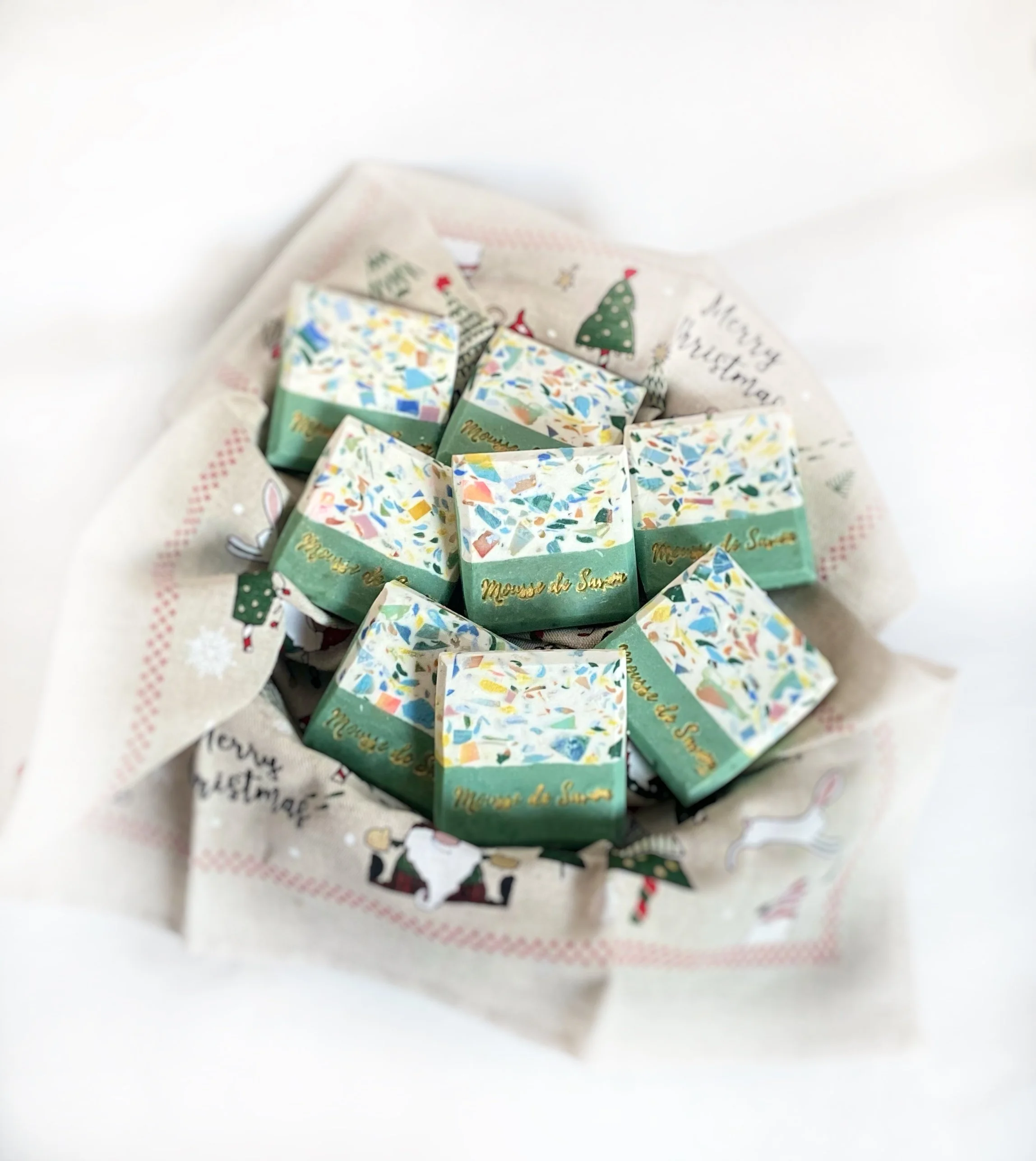 Small decorative soap bars placed on a festive holiday-themed cloth.