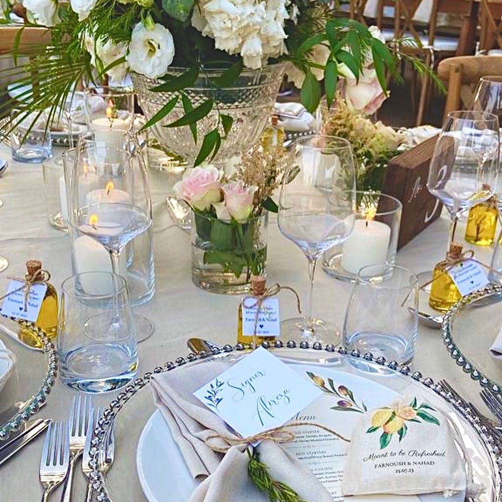 Elegant wedding table setting with floral centerpiece, wine glasses, candles, and place cards.