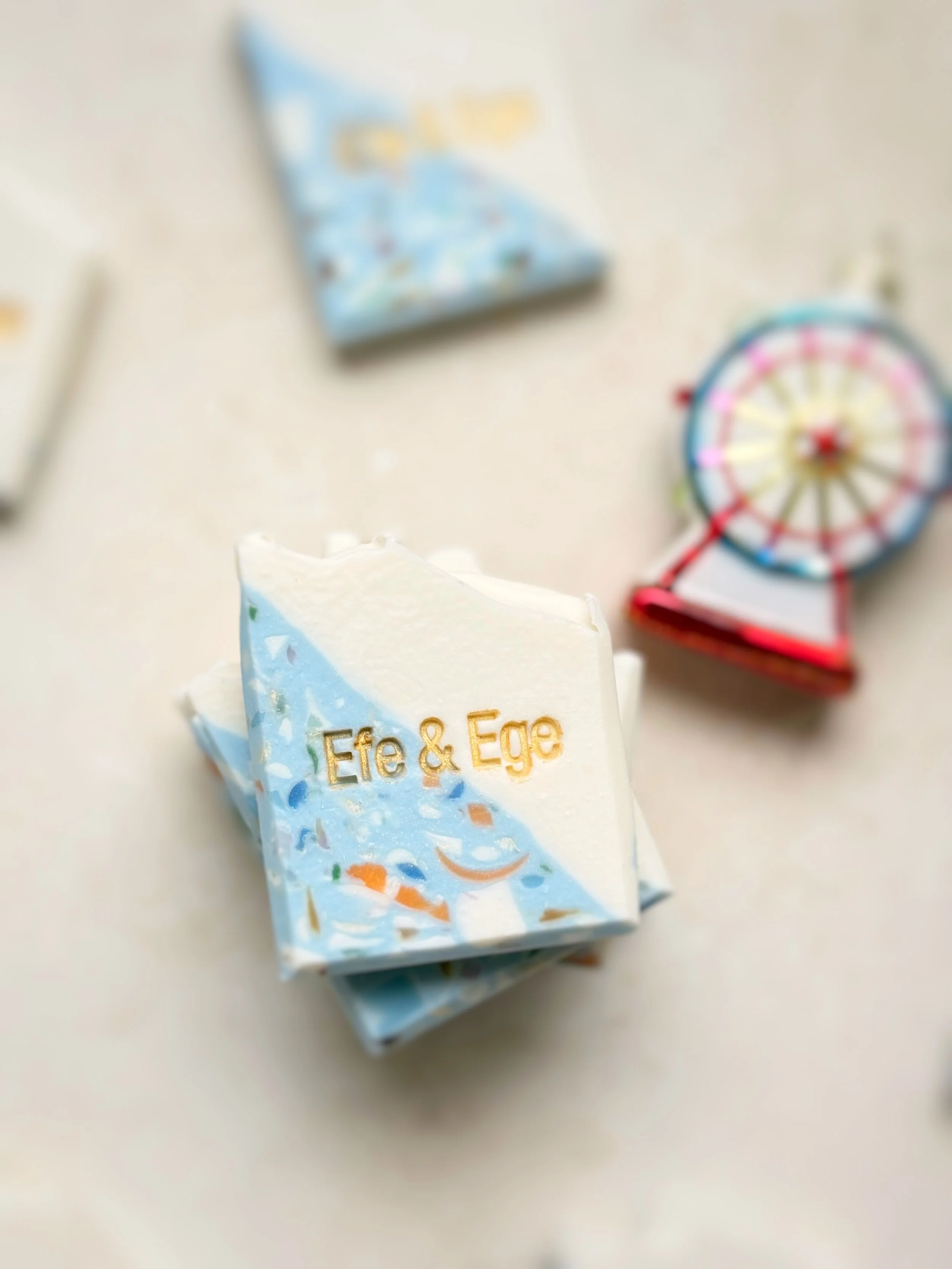 A small soap bar with the text "Efe & Ege" on it, next to a toy Ferris wheel