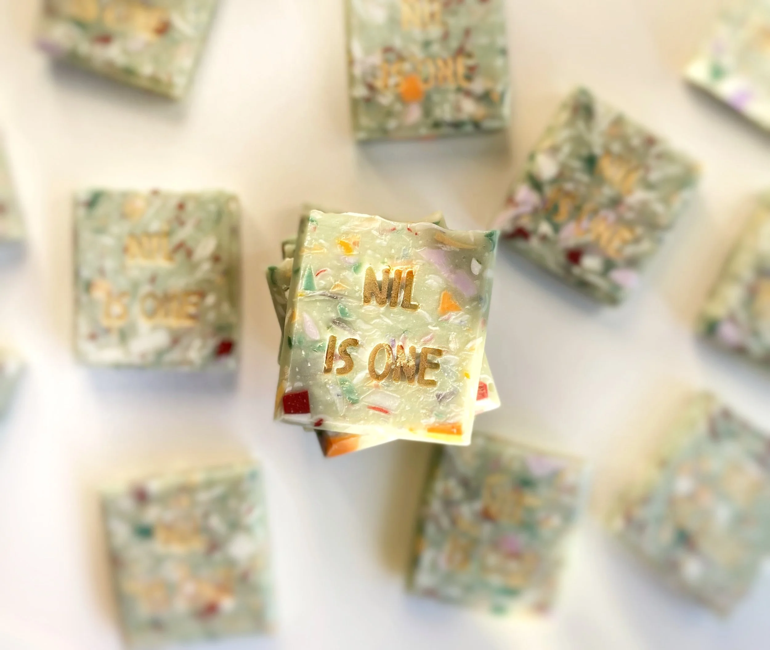Square chocolate pieces with colorful sprinkles and the phrase "NIL IS ONE" inscribed in gold.