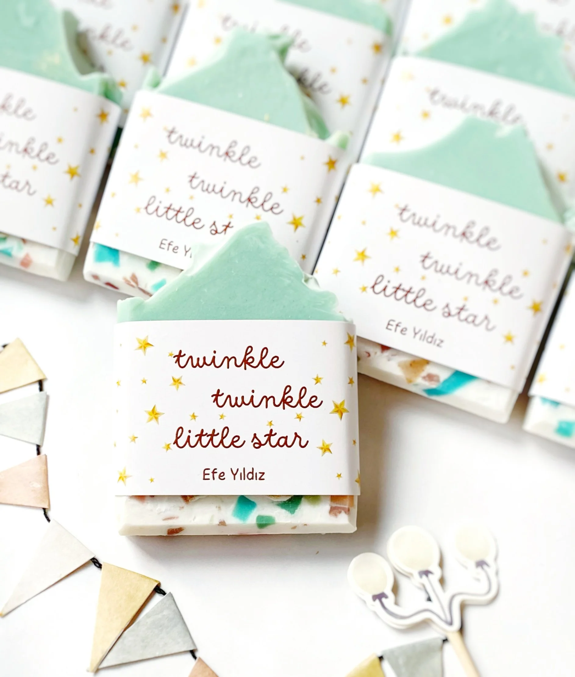 Party favors of soap bars wrapped with star-themed labels reading "twinkle twinkle little star" and the name "Efe Yıldız", surrounded by bunting decorations and small balloon-shaped paper clips.