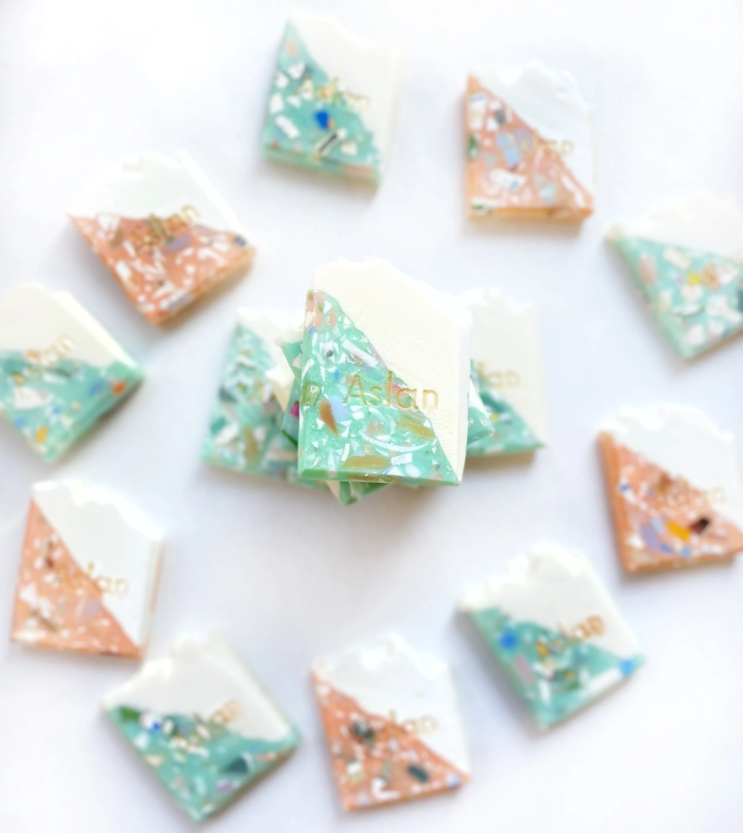 Assorted colorful wrapped candies with the brand name 'Ashton' on some wrappers, spread out on a white surface.