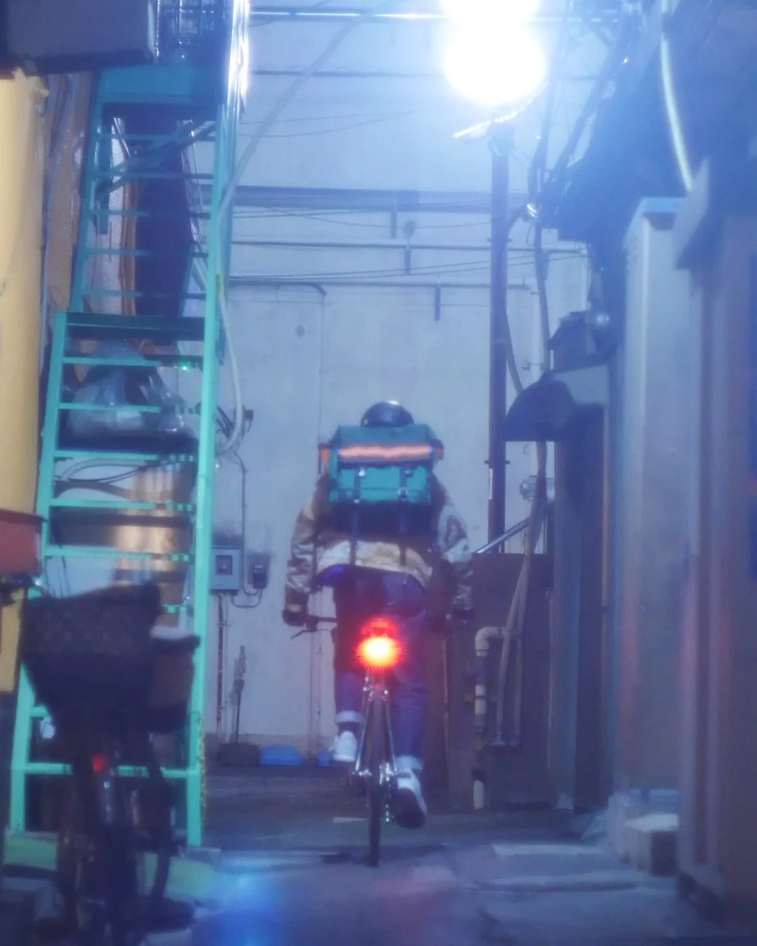 バイクに乗っている人が夜の狭い路地を走っている