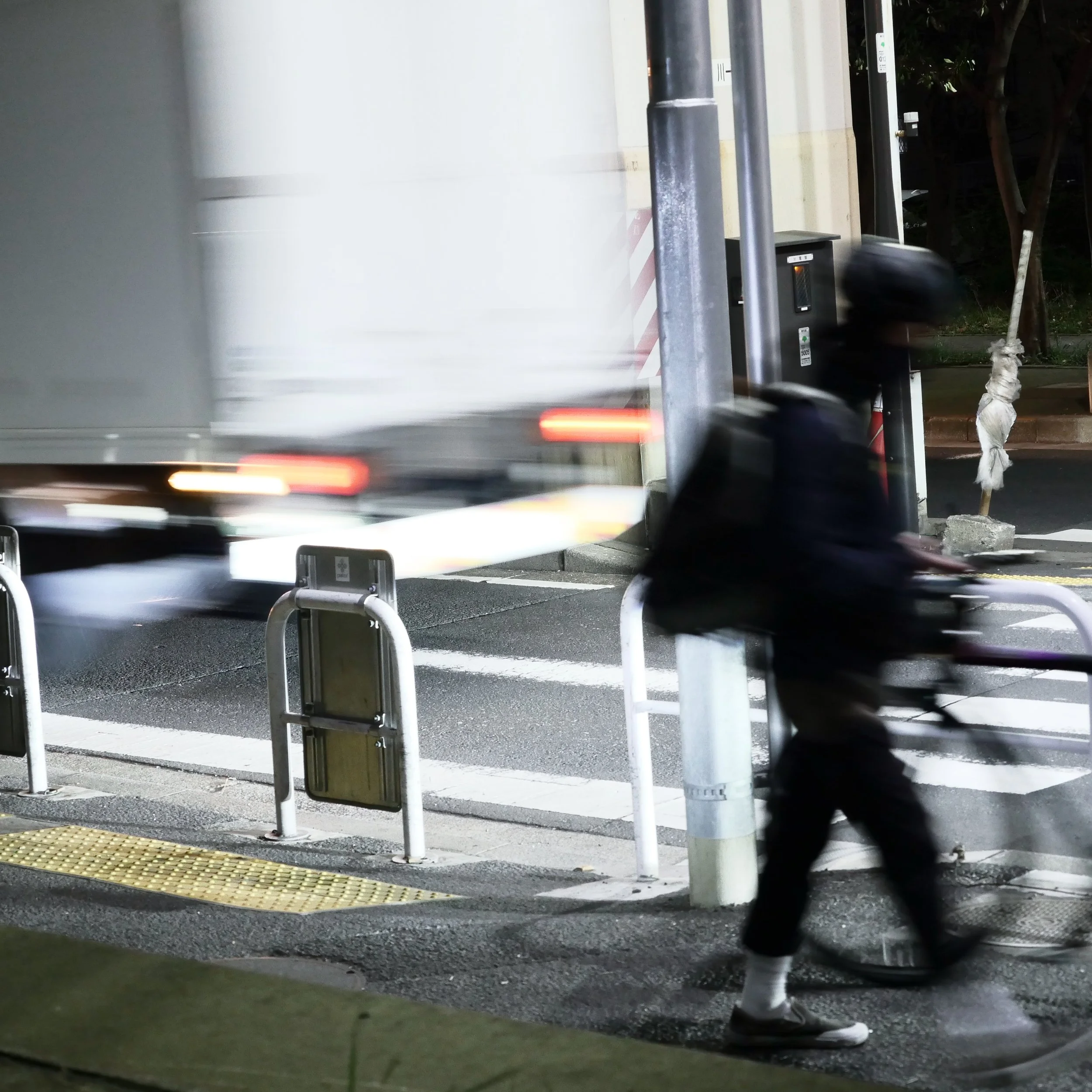 夜の街中を走るバイクと通勤者の自転車に乗る人が通る風景