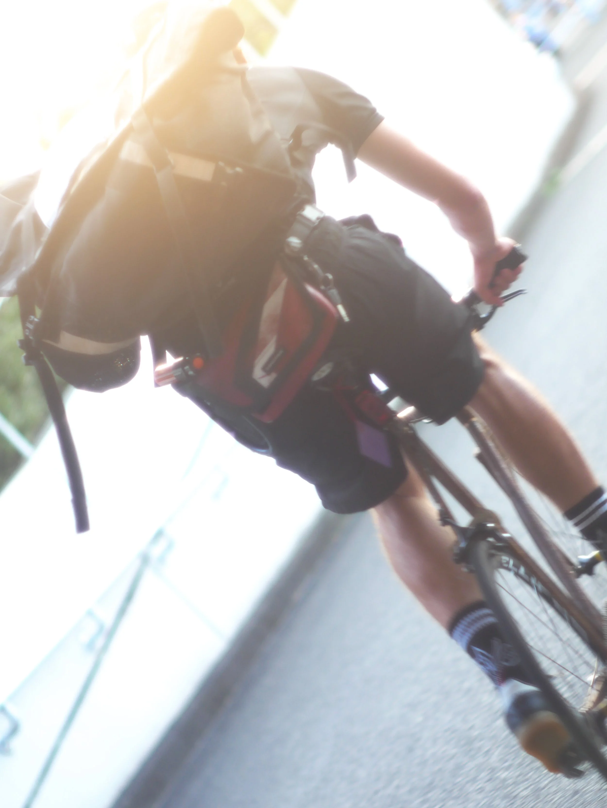 自転車に乗る男性の上半身と荷物を背負った背中の写真