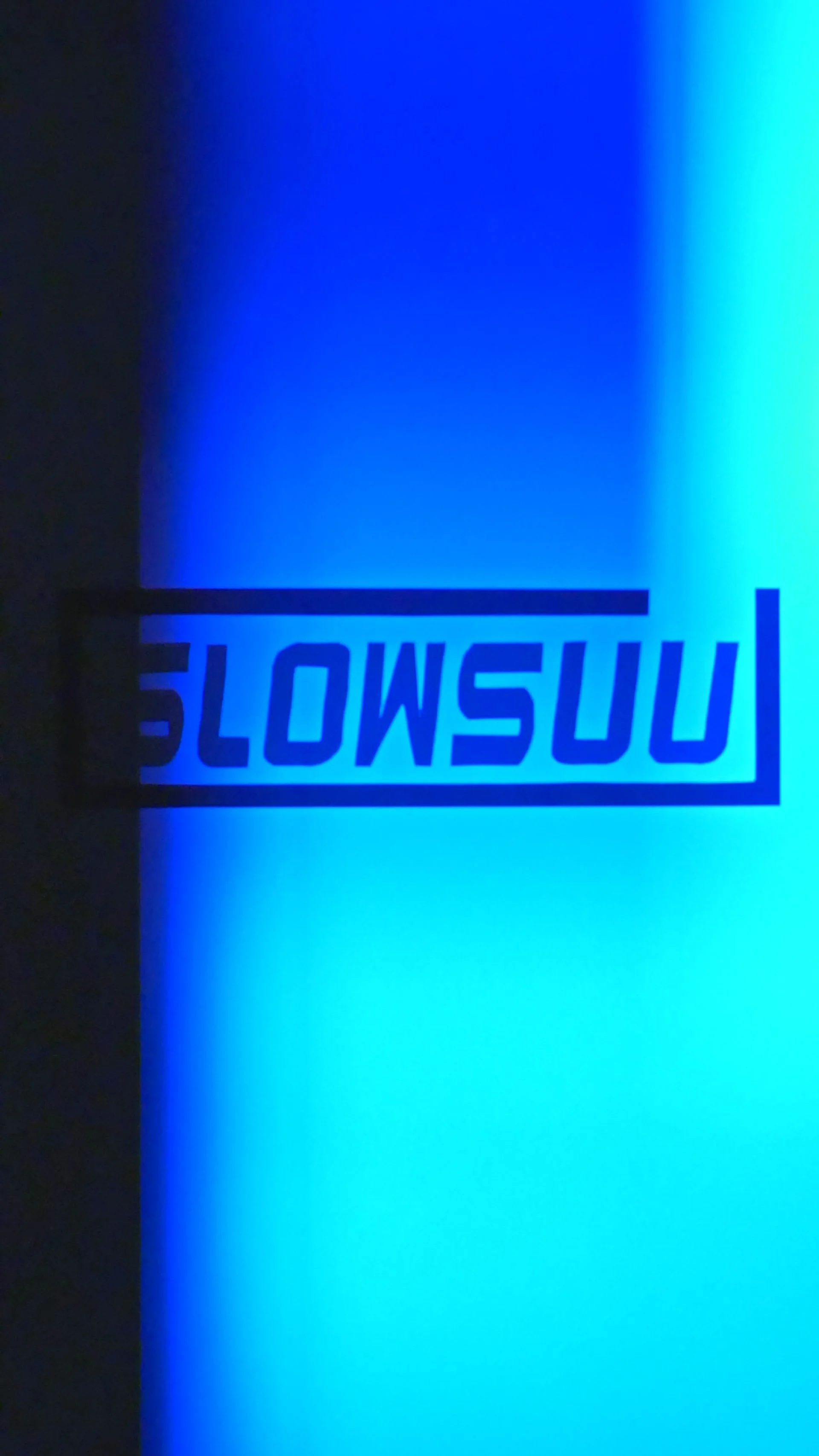 青色の光の背景に反転した黒い文字で「SLOWSU」と書かれている