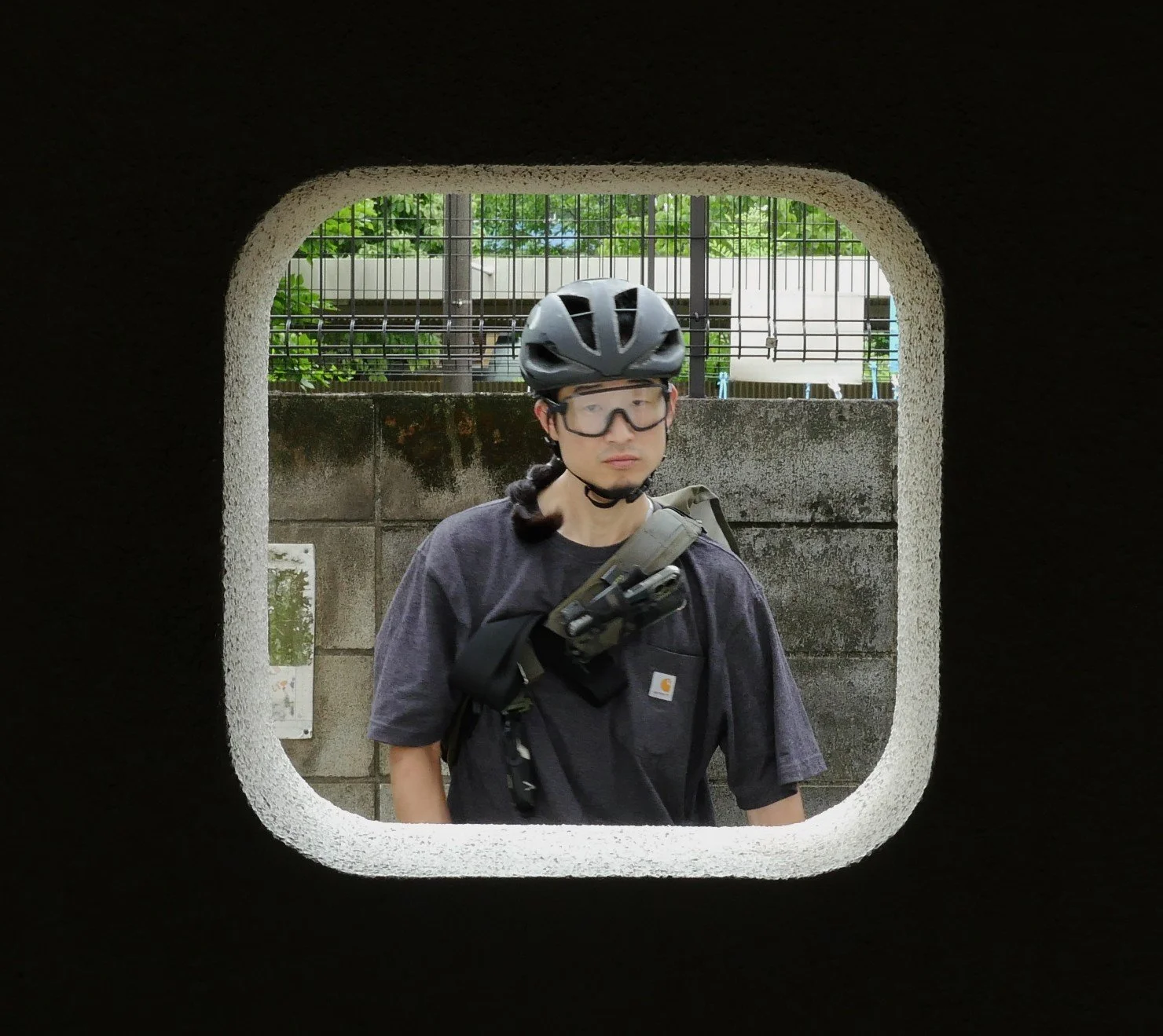 自転車用ヘルメットをかぶった男性が壁の穴を通して見える