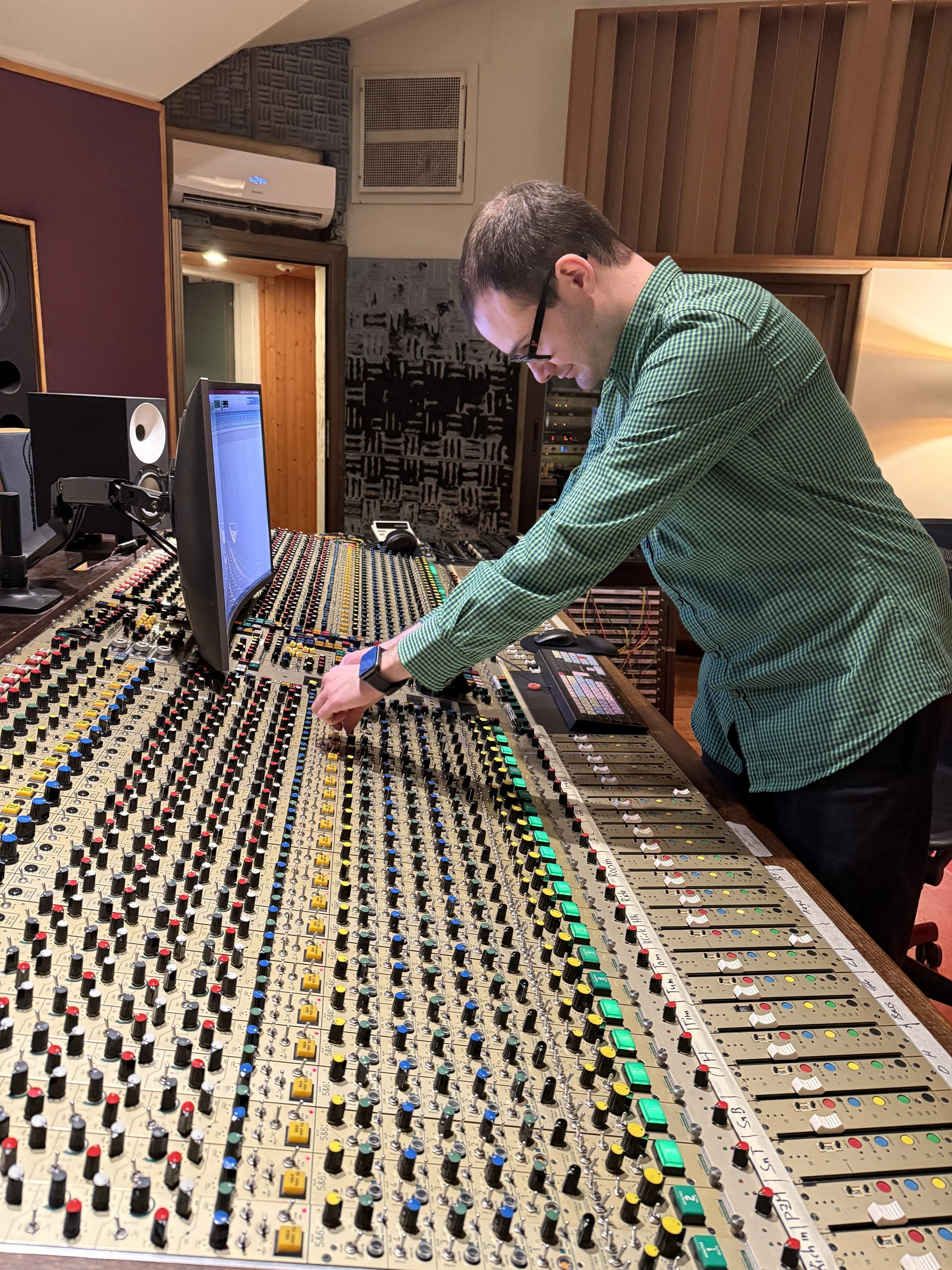 Mann bedient ein großes Tonmischpult in einem Tonstudio.