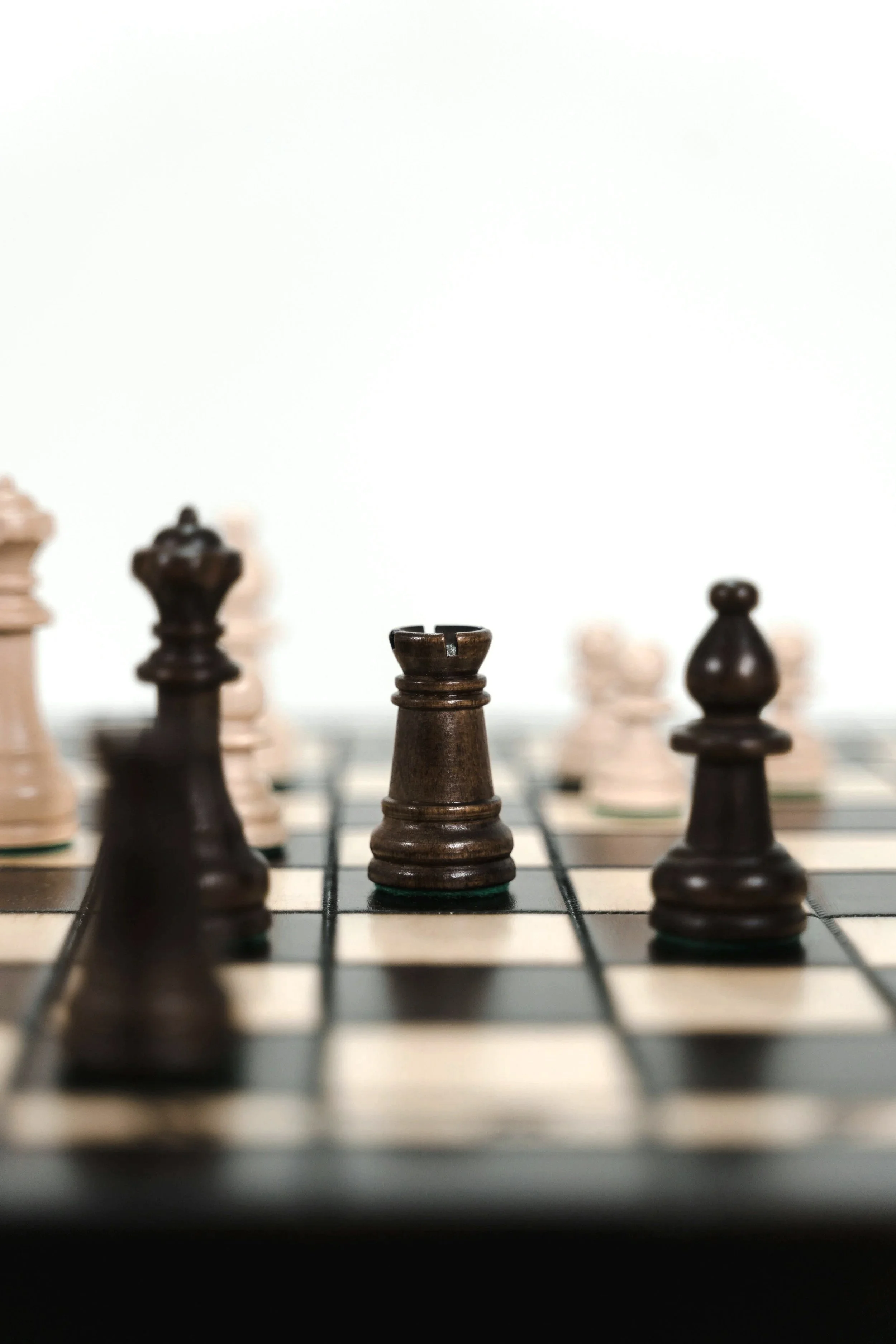 Close-up of a chessboard showing a Clavícula pawn in the foreground with blurred chess pieces in the background.