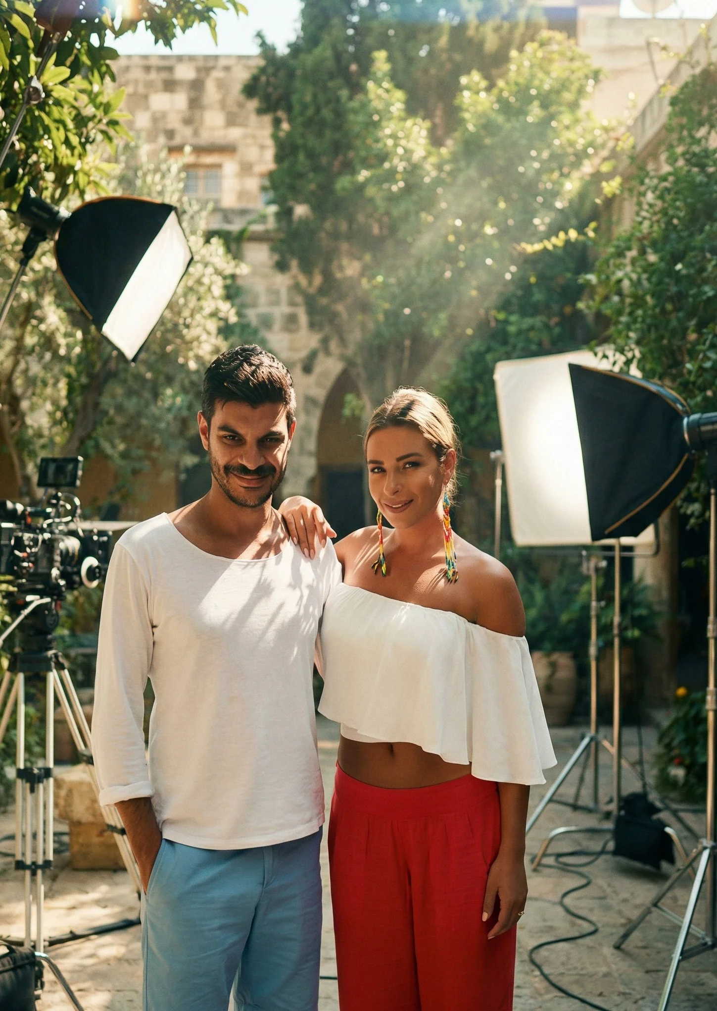 Two people, a man and a woman, standing outside surrounded by greenery and film equipment, including lights and a camera, on a sunny day.Julien Maalouf