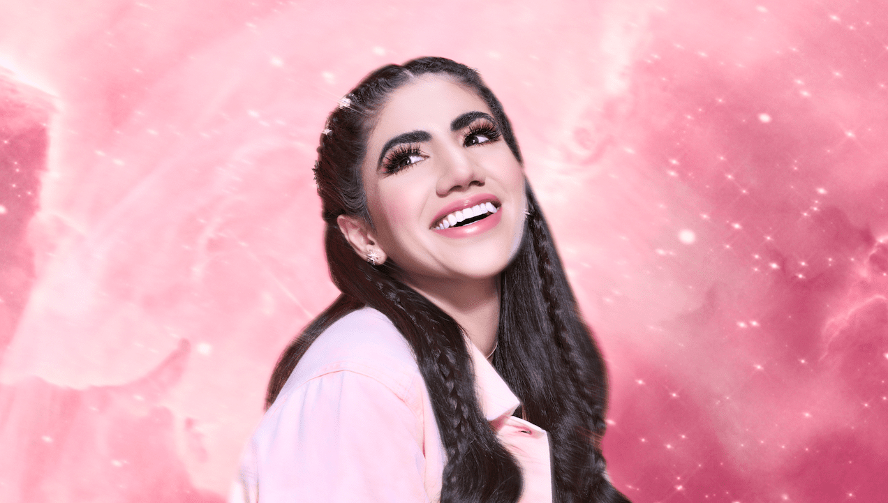 A woman with long dark hair styled in braids, smiling against a pink cosmic background with stars and nebulae.