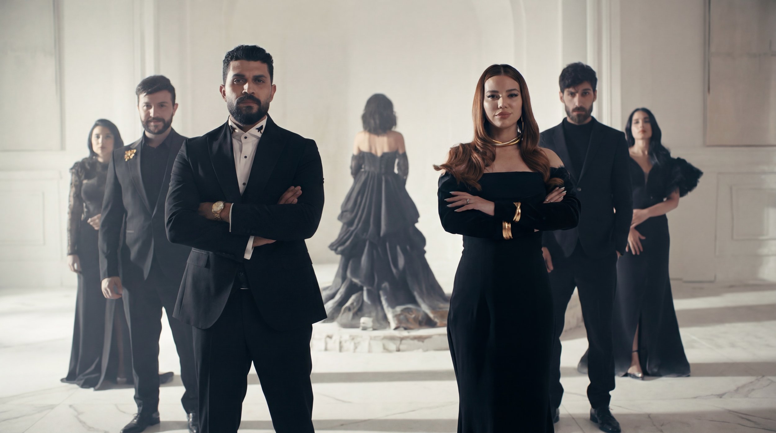 Six well-dressed people standing in a grand, elegant room with a sculpture in the background. Three men and three women, all with confident expressions, pose with crossed arms. Julien Maalouf