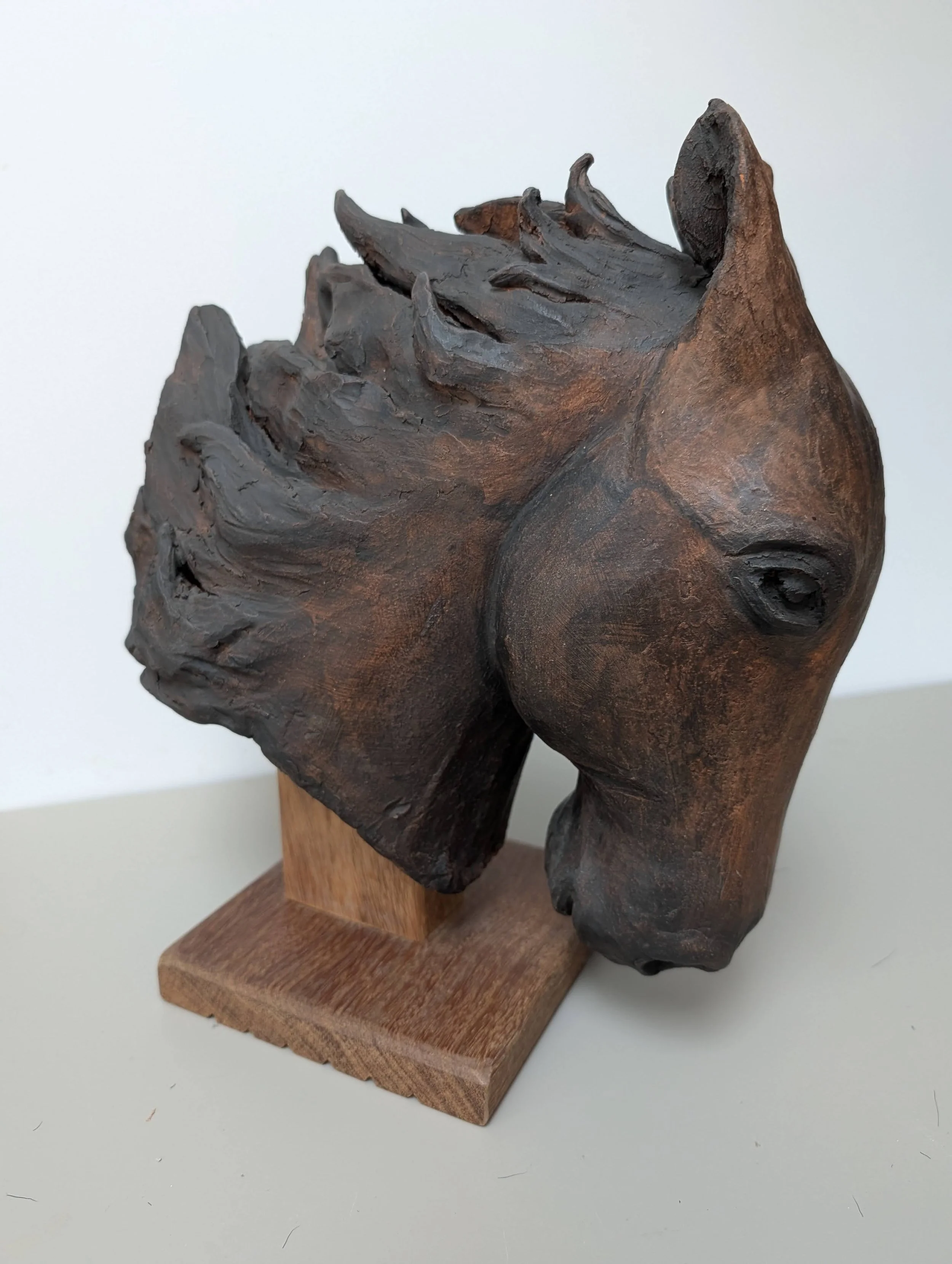 Tête de cheval sculptée sur une base en bois.