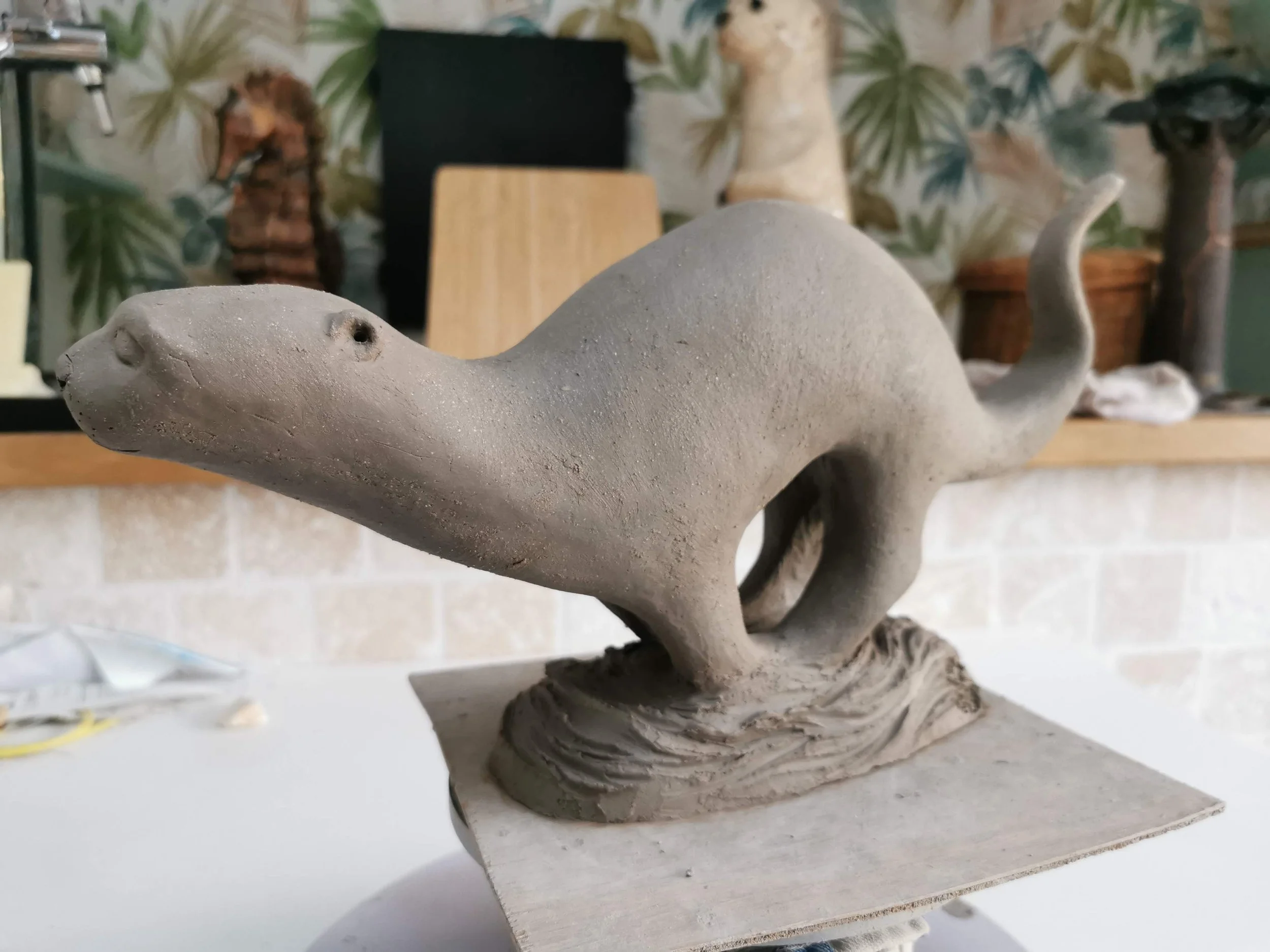 Sculpture en argile représentant une loutre qui court.